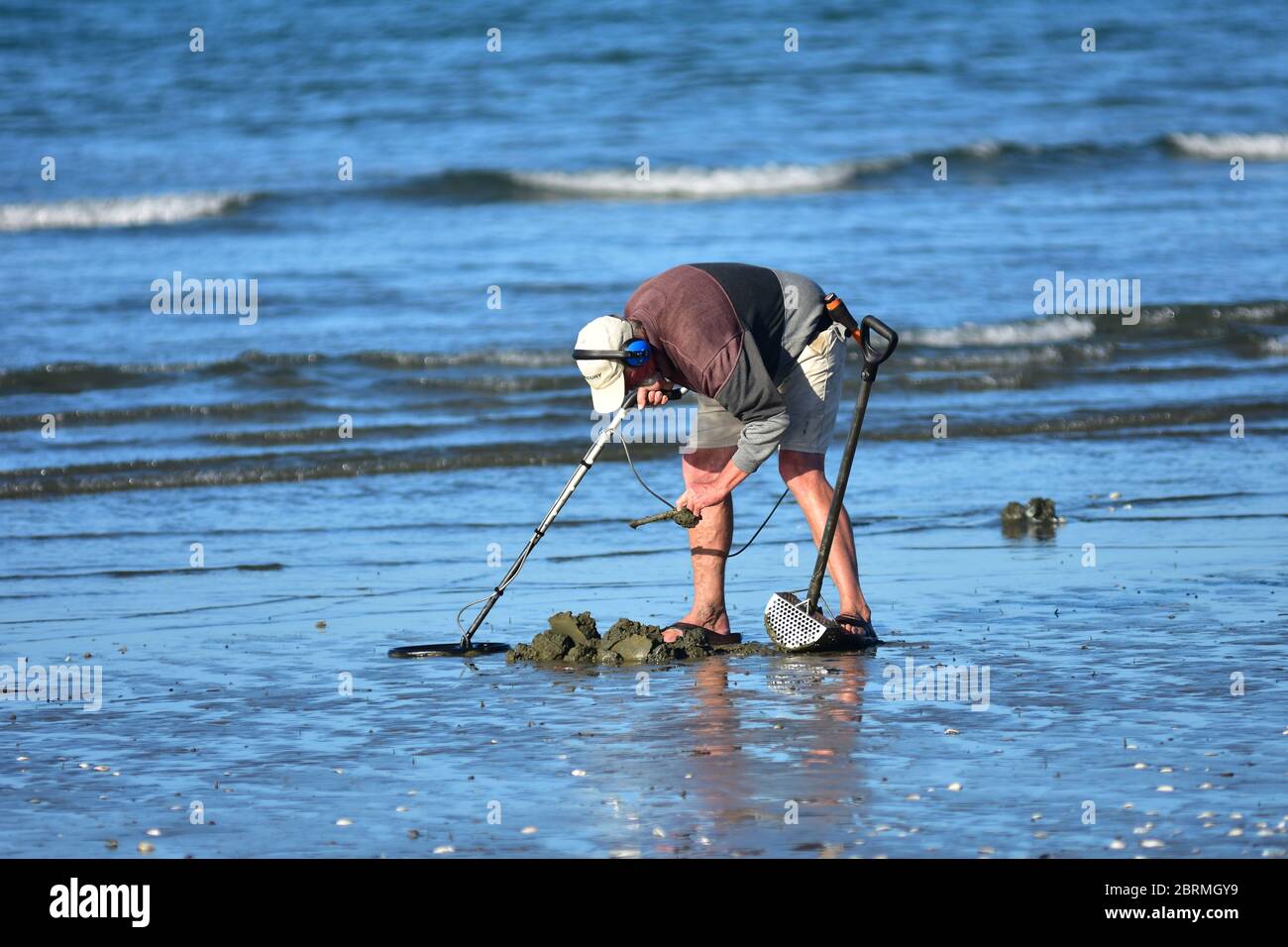 Cacciatore di tesori con metal detector scavare in spiaggia sabbia sulla  riva del mare Foto stock - Alamy