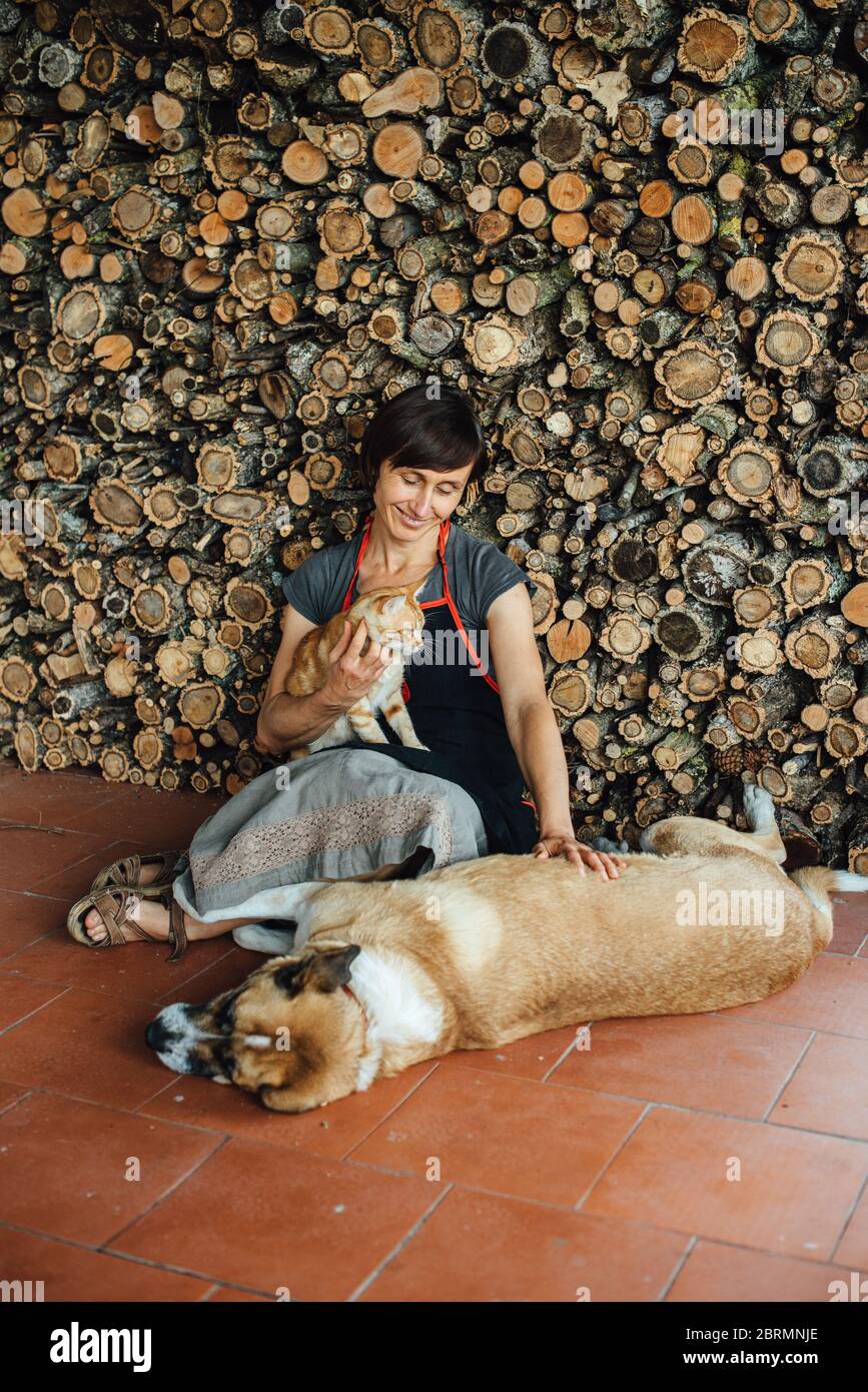 Donna di legno che riposa con animali domestici mentre si siede sul pavimento Foto Stock