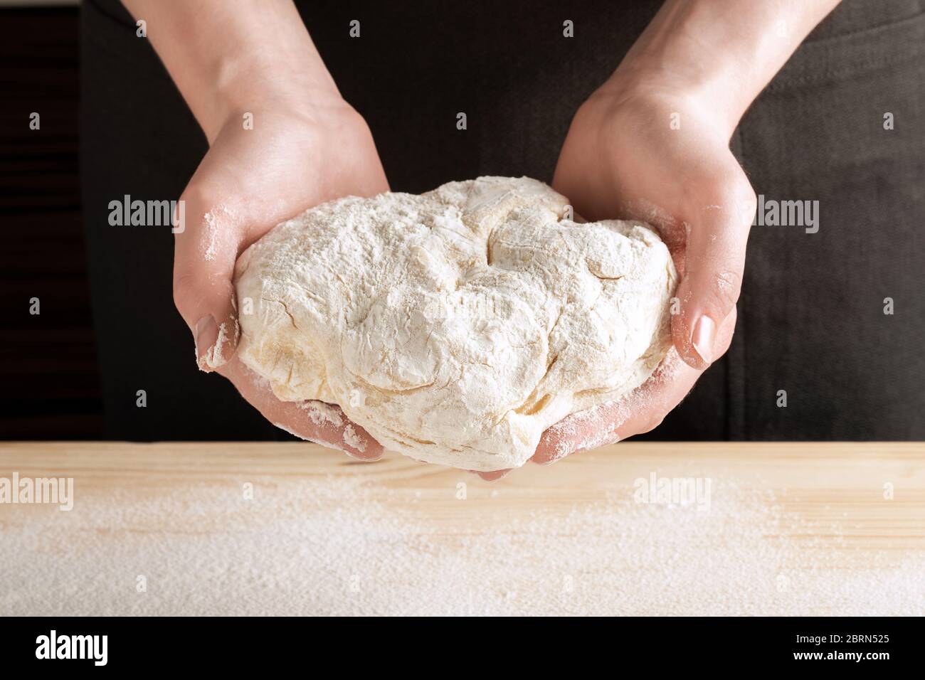 Vista frontale delle mani femminili trattenete l'impasto per cuocere pizza, pane, torte o torte. Ricetta passo-passo per cucinare ravioli o gnocchi, passo 5. Foto Stock