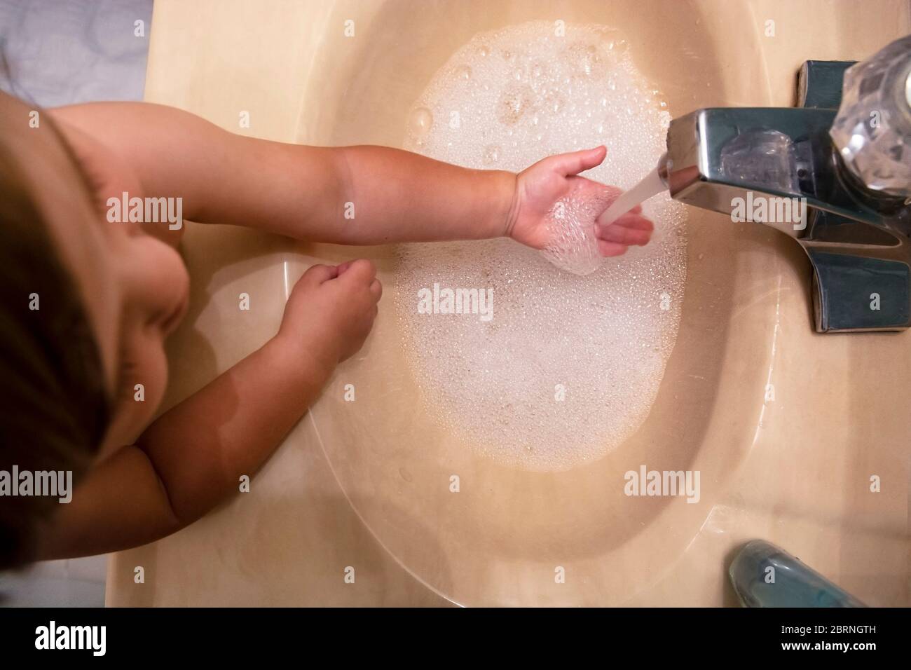 Ragazzo in bagno che si lava le mani nel lavandino Foto Stock