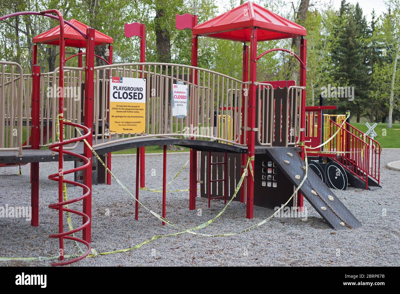 Blocco del coronavirus: Nastro giallo intorno al parco giochi vuoto nel parco cittadino con cartello chiuso per limitare la diffusione del COVID 19 Foto Stock