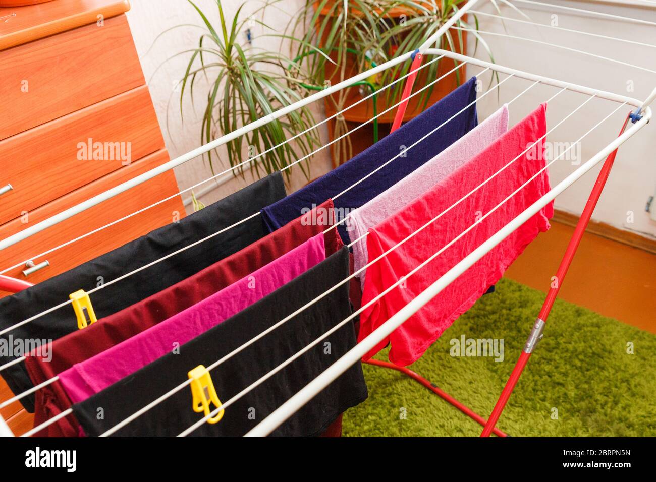 Asciugando i vestiti su un asciugatore mobile. Biancheria colorata sull'asciugatore nell'appartamento. Foto Stock