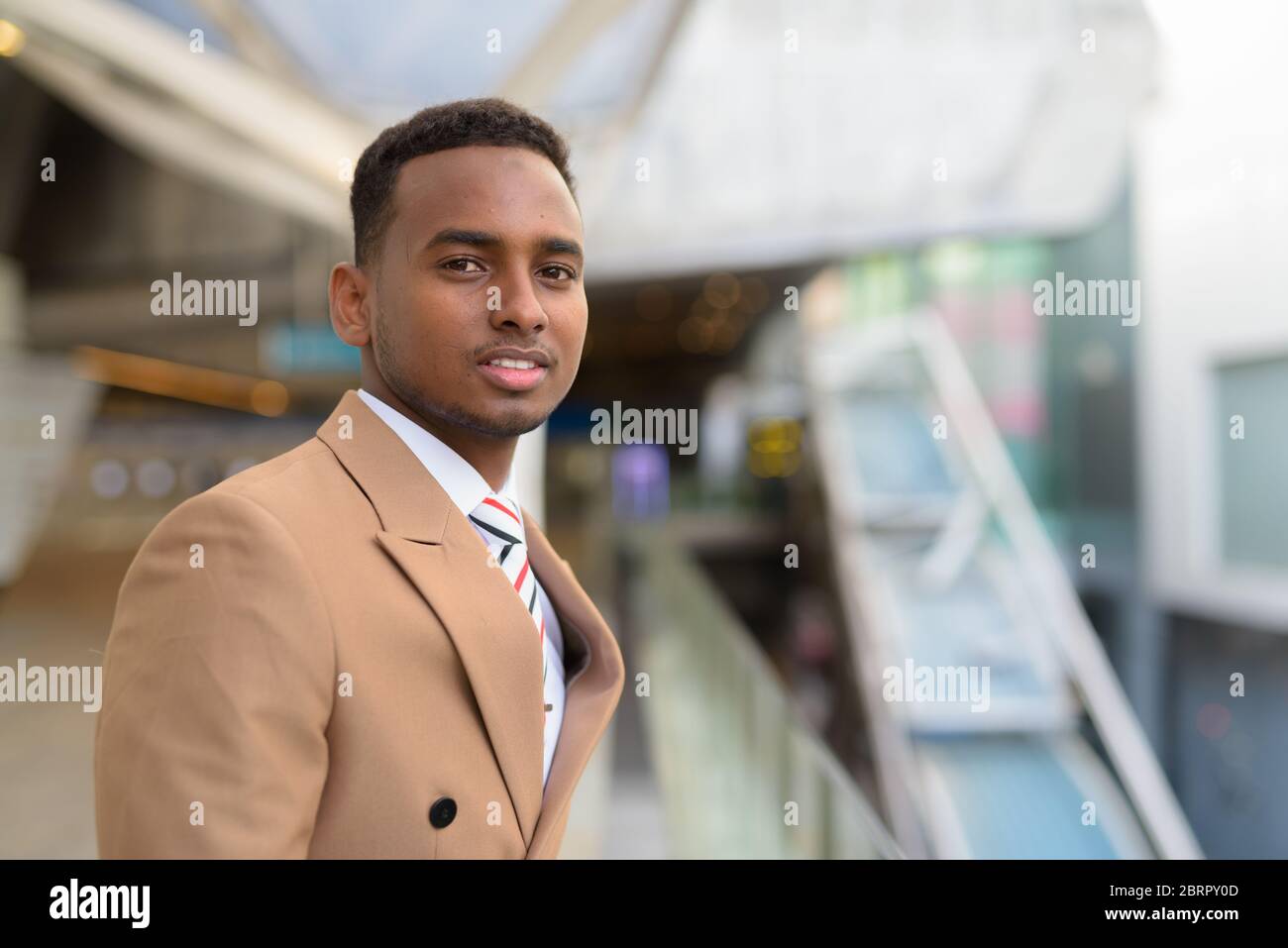 Felice giovane bell'uomo d'affari africano a passerella in città Foto Stock