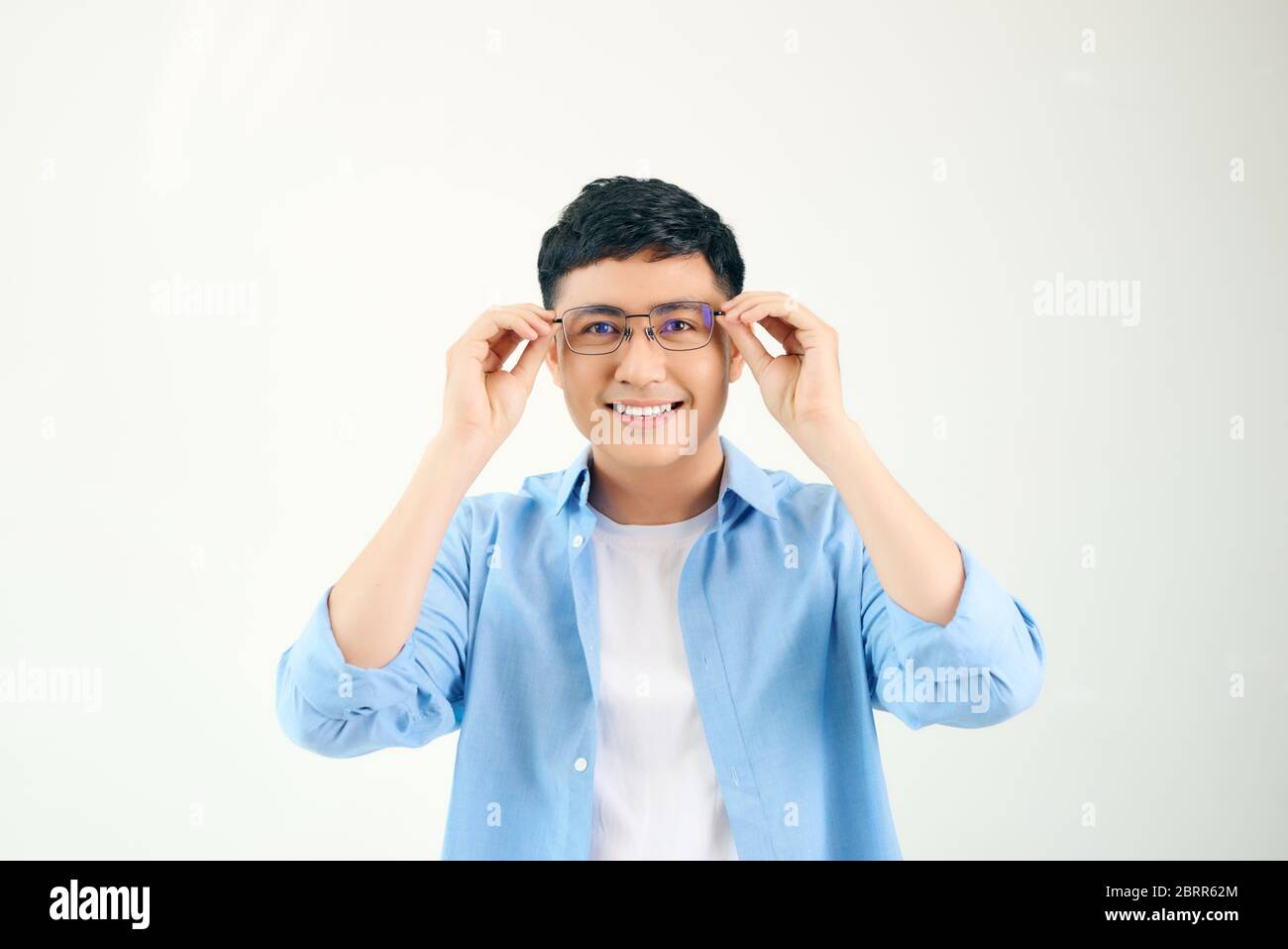 Primo piano di un ragazzo amichevole che indossa occhiali. Giovane asiatico che regola gli occhiali e fissa la fotocamera attraverso l'obiettivo. Visione e cura degli occhi Foto Stock