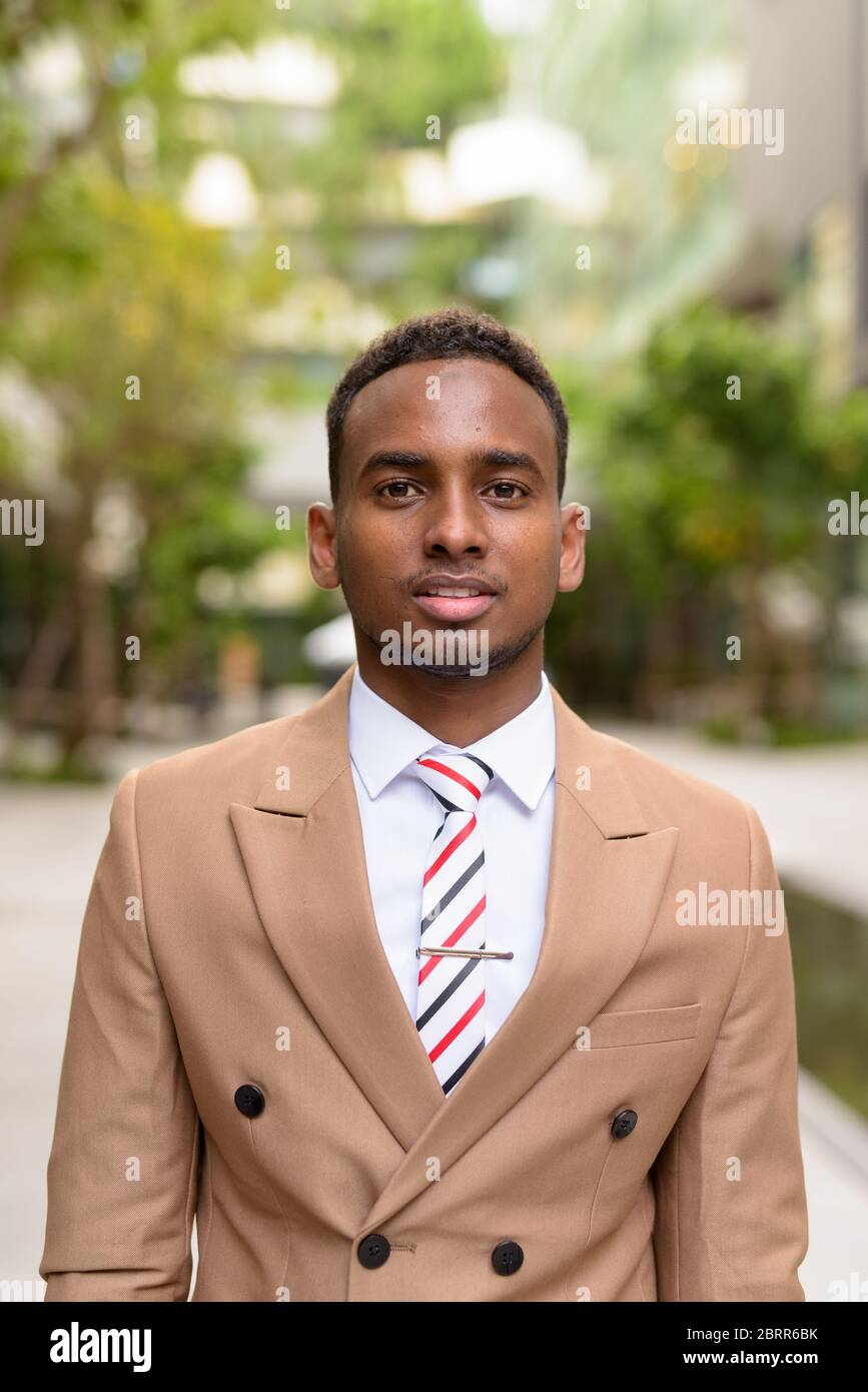 Giovane bell'uomo d'affari africano in città con la natura Foto Stock