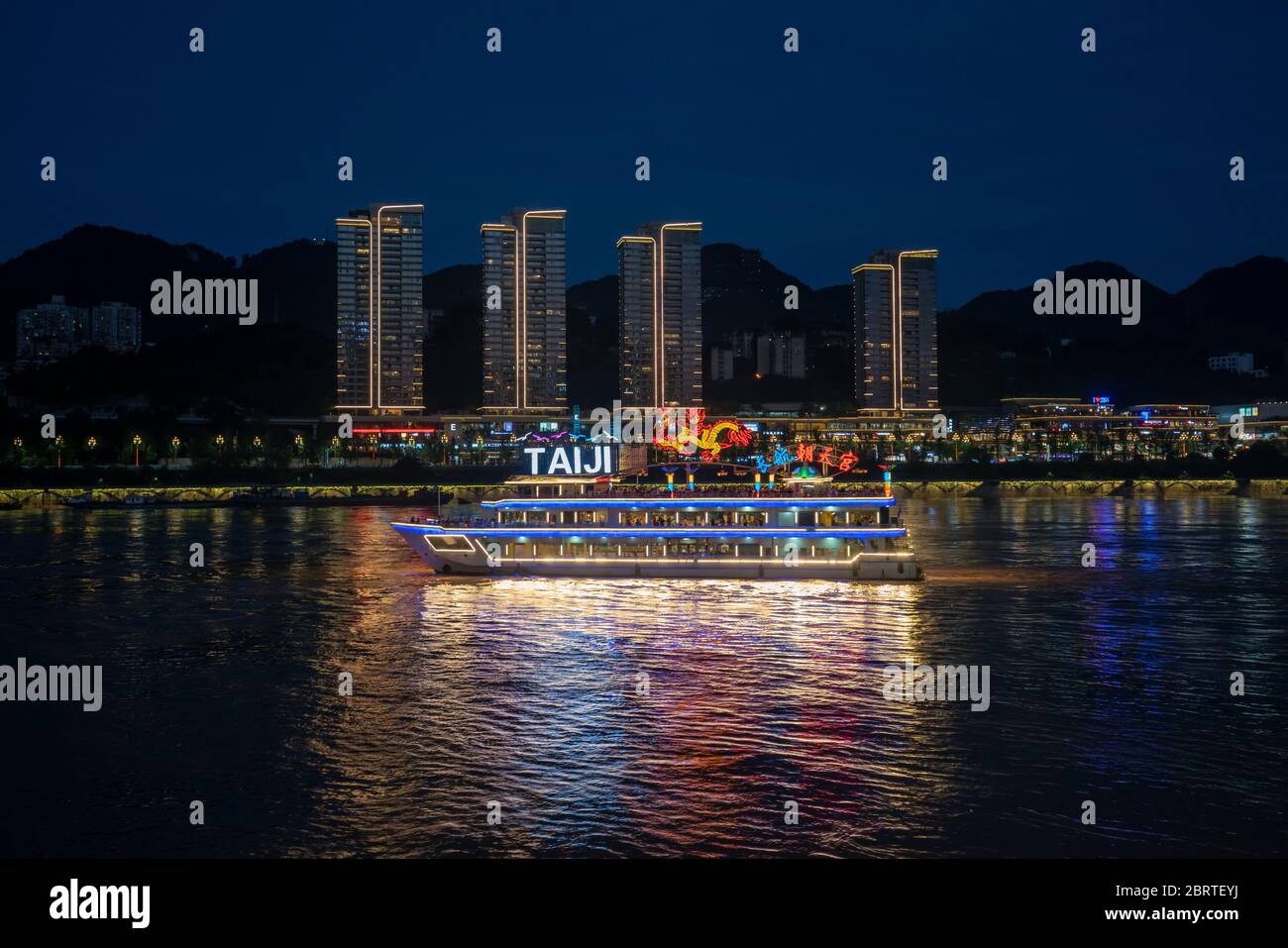 Chongqing, Cina - Agosto 2019 : nave turistica di lusso passeggeri che naviga sui fiumi Yangtze e Jialing di notte con grattacieli illuminati in t Foto Stock