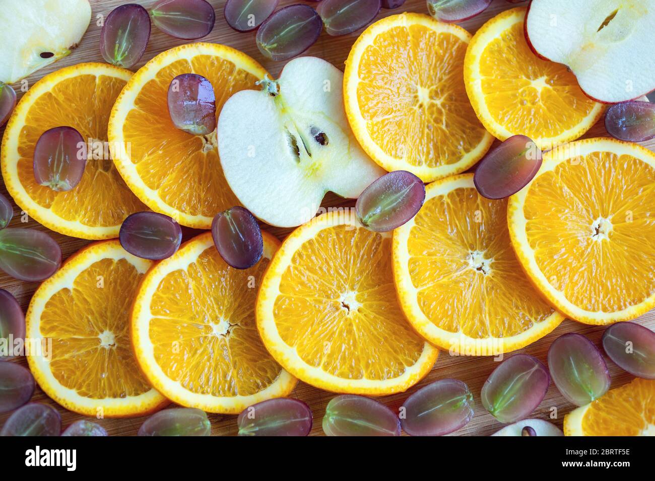 Primo piano della composizione delle fette di arancia, mela e uva. Concetto di snack vegetariano con frutta sana Foto Stock