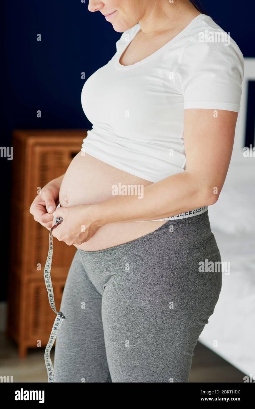 Donna incinta misurando il suo addome Foto Stock