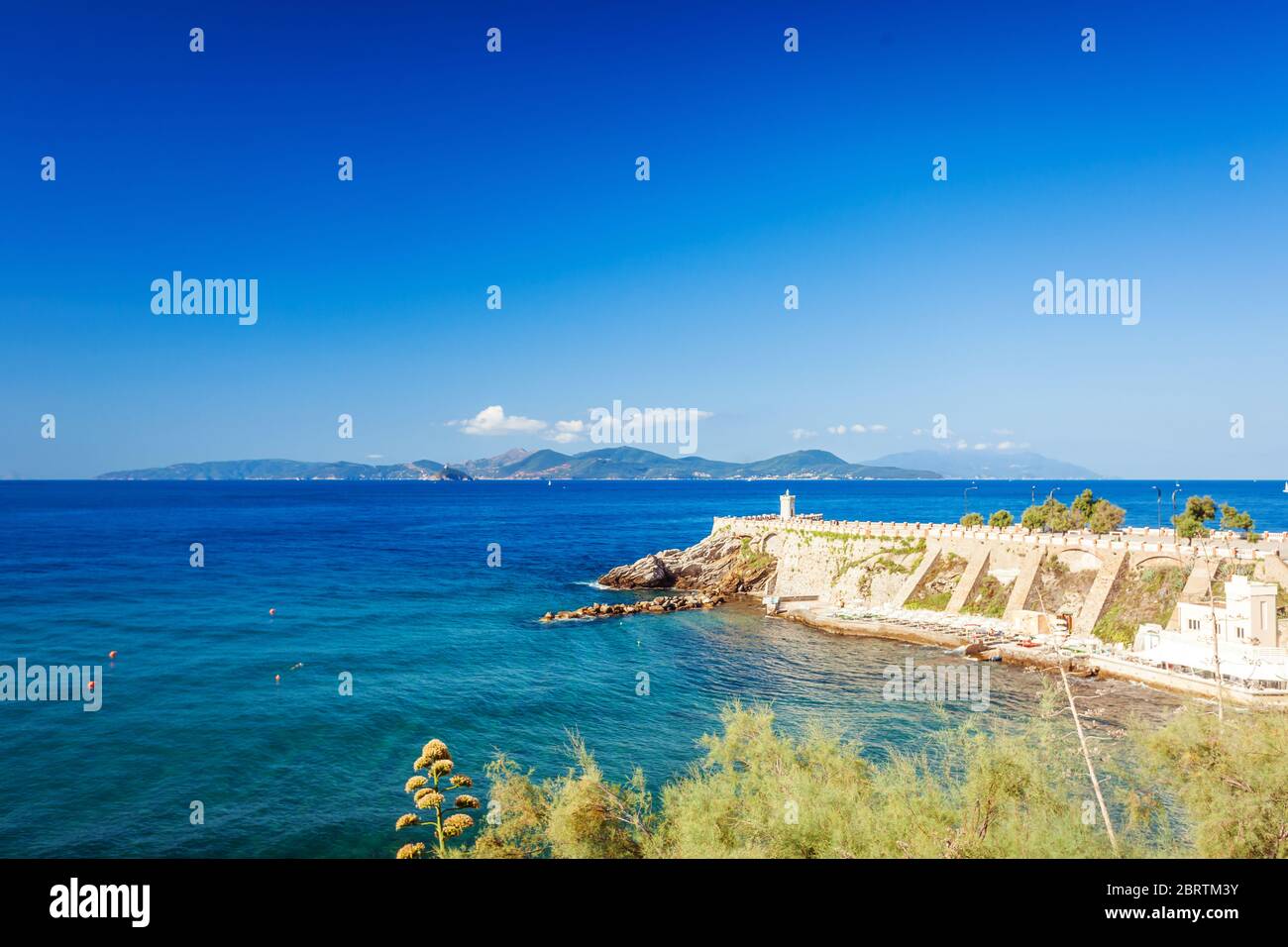 Isola d'Elba all'orizzonte visibile contro il faro e Piazza Bovio a Piombino, Toscana, italia Foto Stock