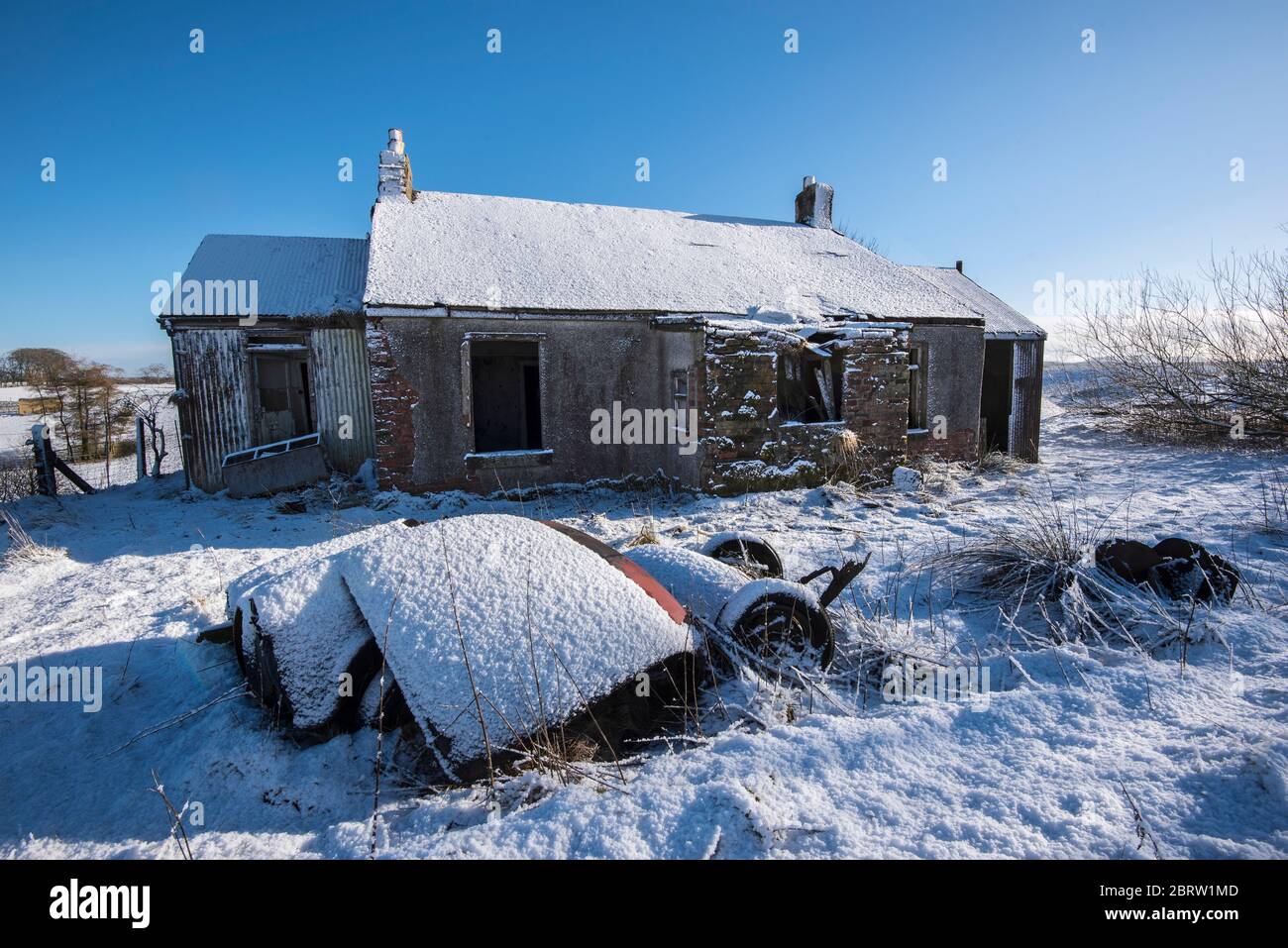 Casa derelict in neve coperta ambiente rurale nella campagna Lamarkshire Scozia. Foto Stock