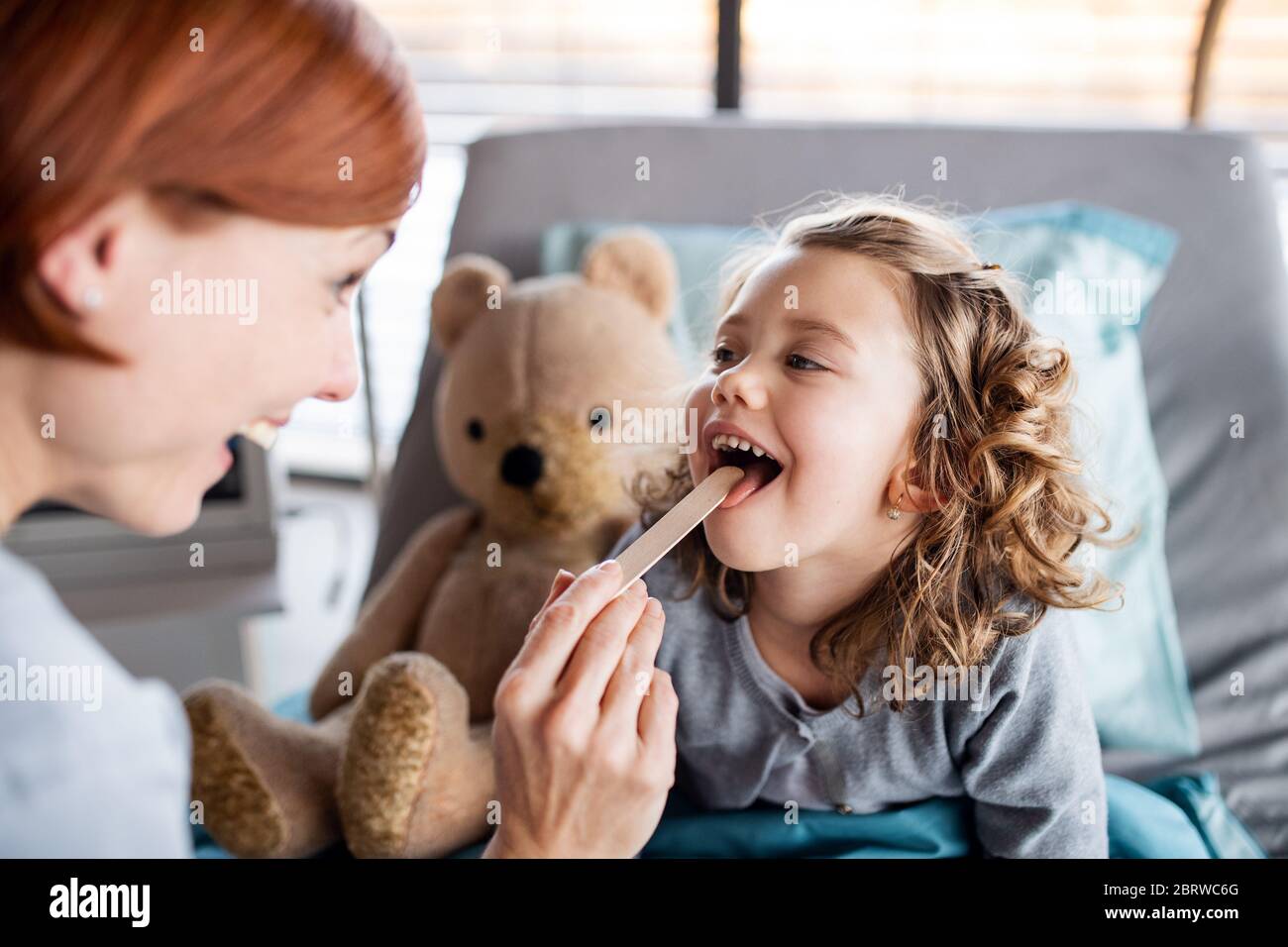Dottore femminile che esamina la bambina a letto in ospedale. Foto Stock