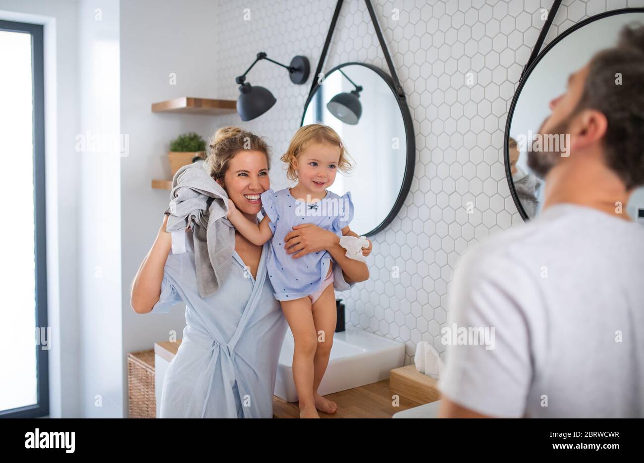Giovane famiglia con piccola figlia al chiuso in bagno, che parla. Foto Stock