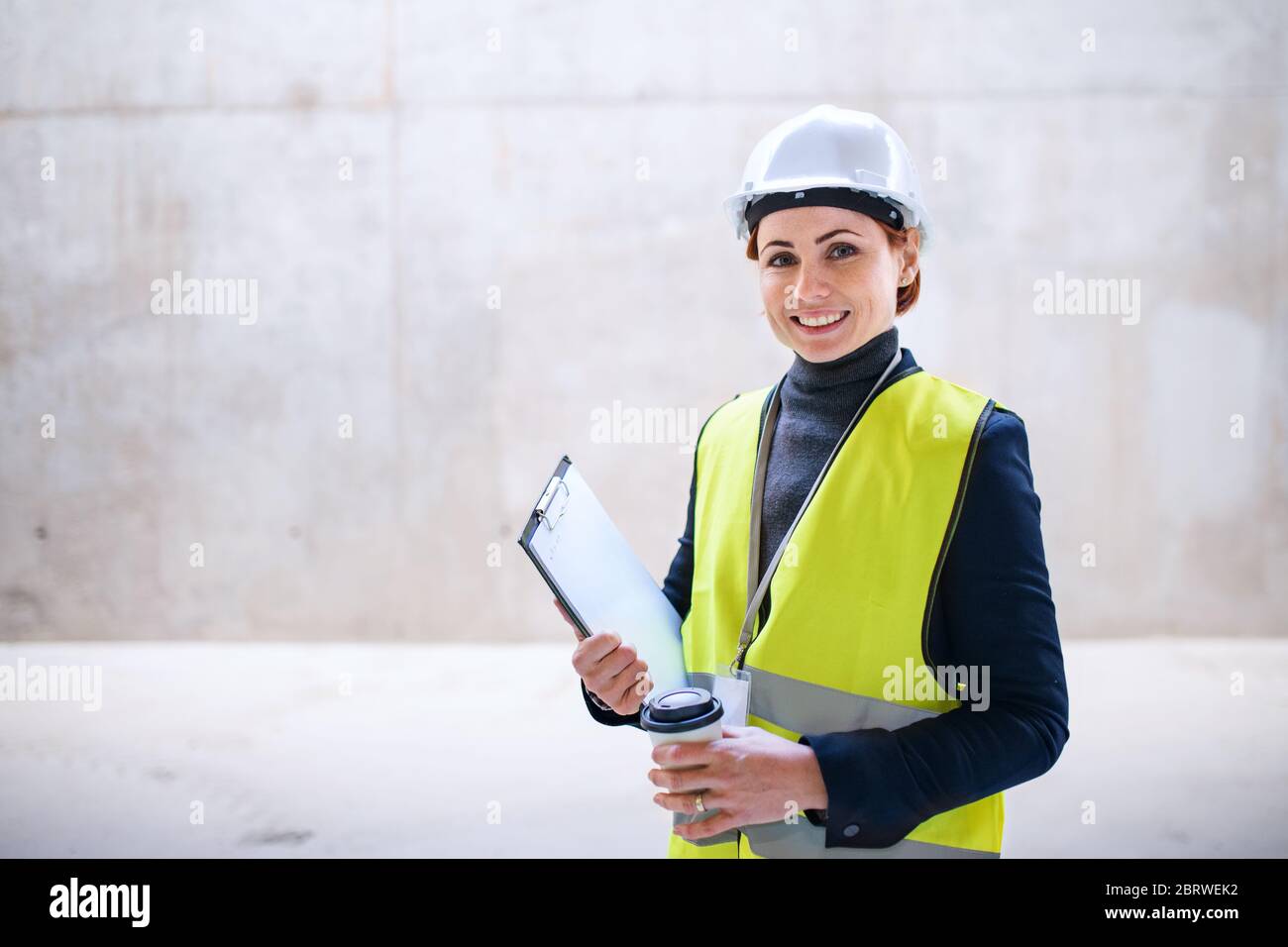 Una donna ingegnere in piedi contro muro di cemento sul cantiere. Foto Stock