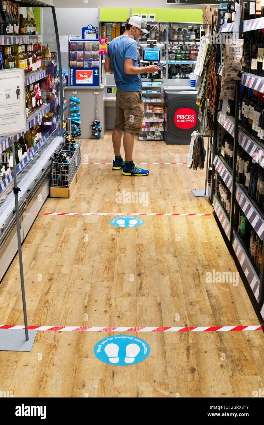 Covid-19 social distancing pavimento marcature al checkout del negozio Coop a Settle, North Yorkshire, Regno Unito Foto Stock