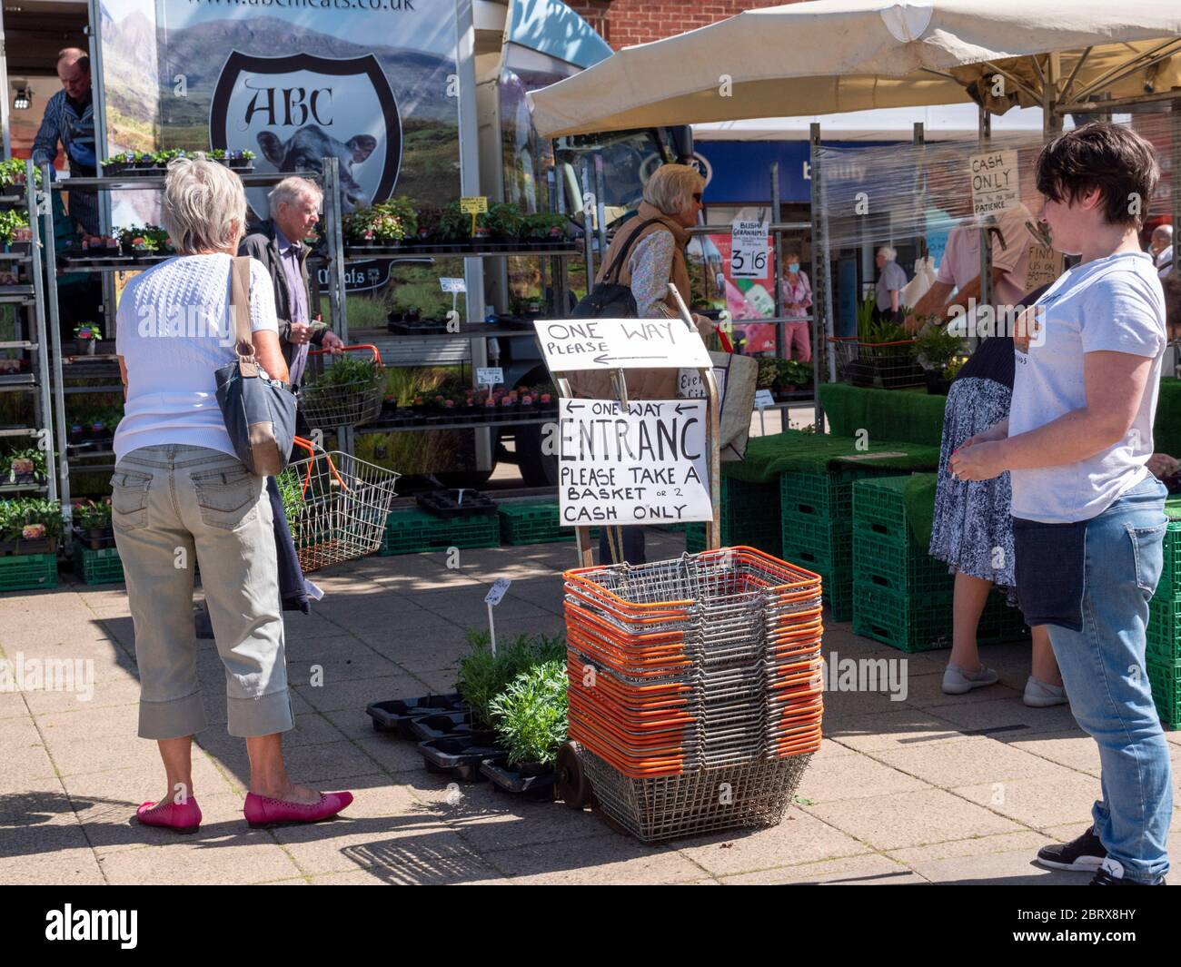 Una bancarella di mercato con cartelli e un sistema di senso unico per mantenere la distanza sociale dei clienti in coda durante l'epidemia di covid-19 a St Ives Cambridgeshire UK Foto Stock