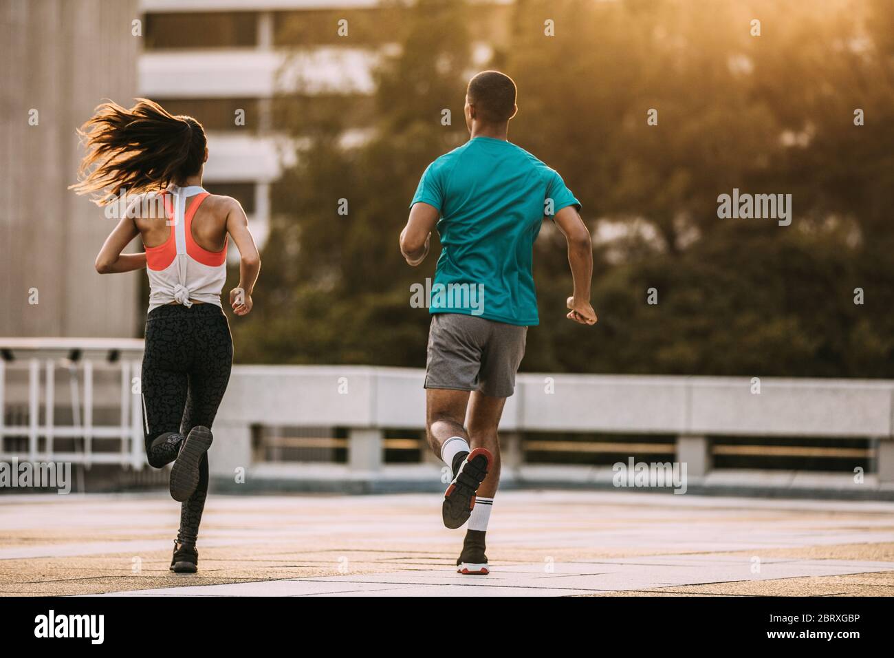 Vista posteriore di un uomo e di una donna che corrono insieme al mattino. Amici in sport indossare jogging insieme in città. Foto Stock