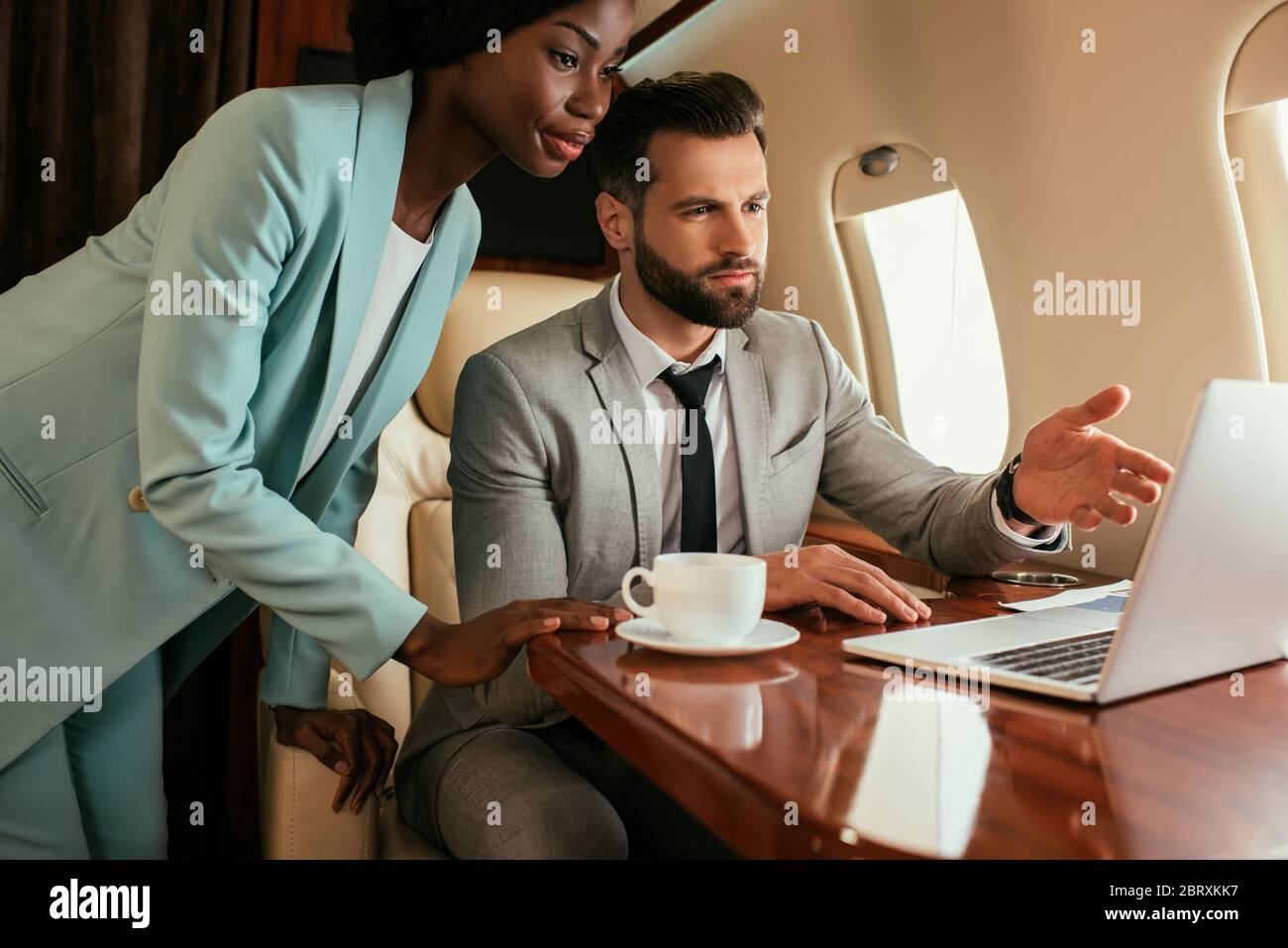 uomo d'affari serio che punta con il dito contro il laptop vicino afroamericano imprenditore Foto Stock