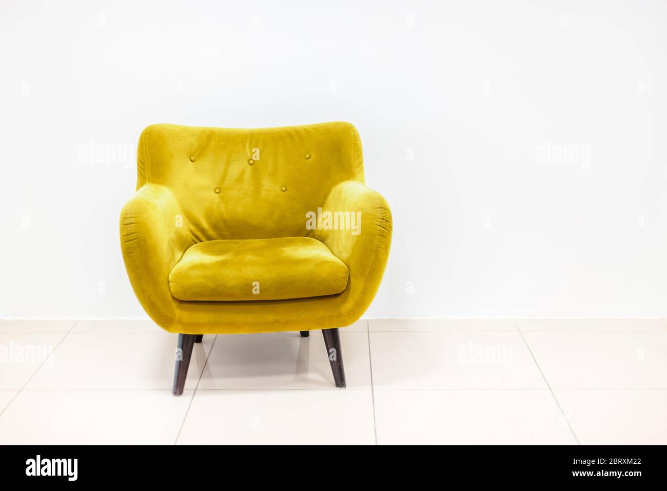 Concetto minimo di vita interna con poltrona di colore giallo dorato brillante su pavimento bianco e sfondo. Mockup da parete in stile scandinavo. Foto Stock