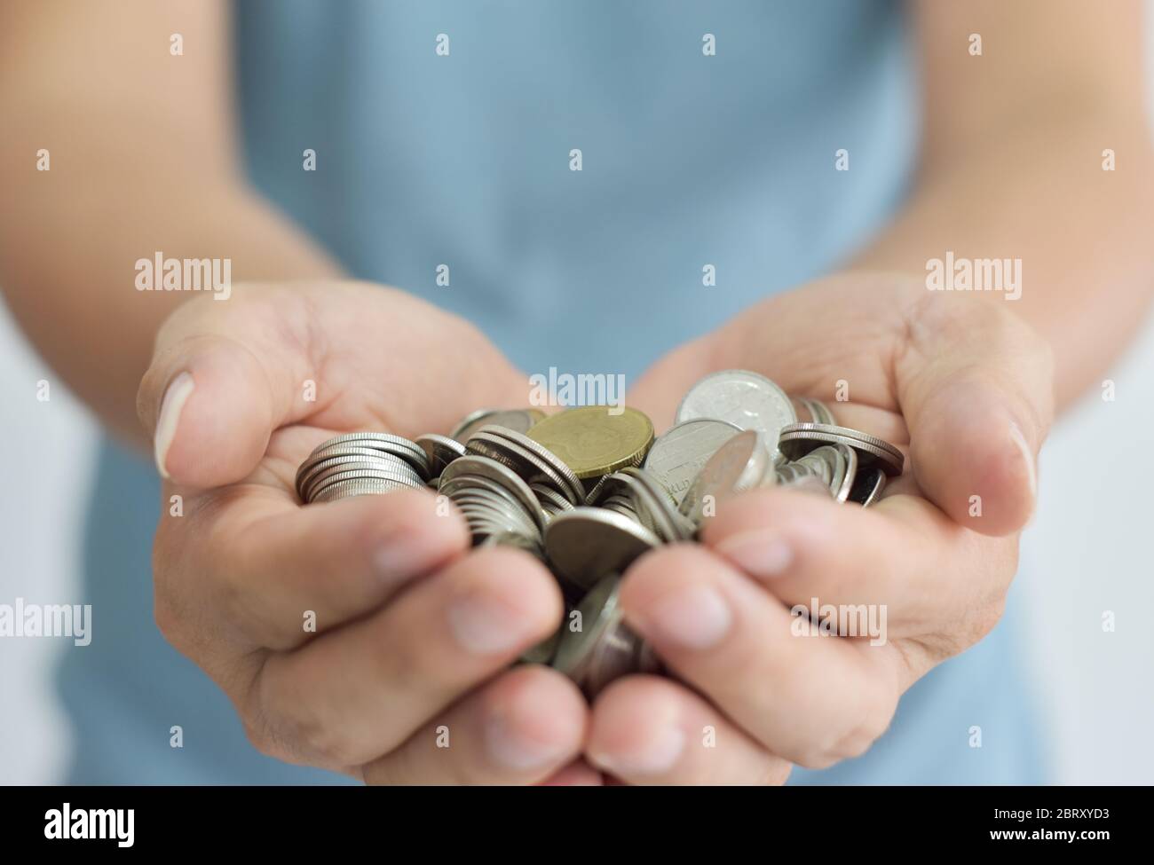 Monete in due mani. Concetto di risparmio di denaro. Foto Stock