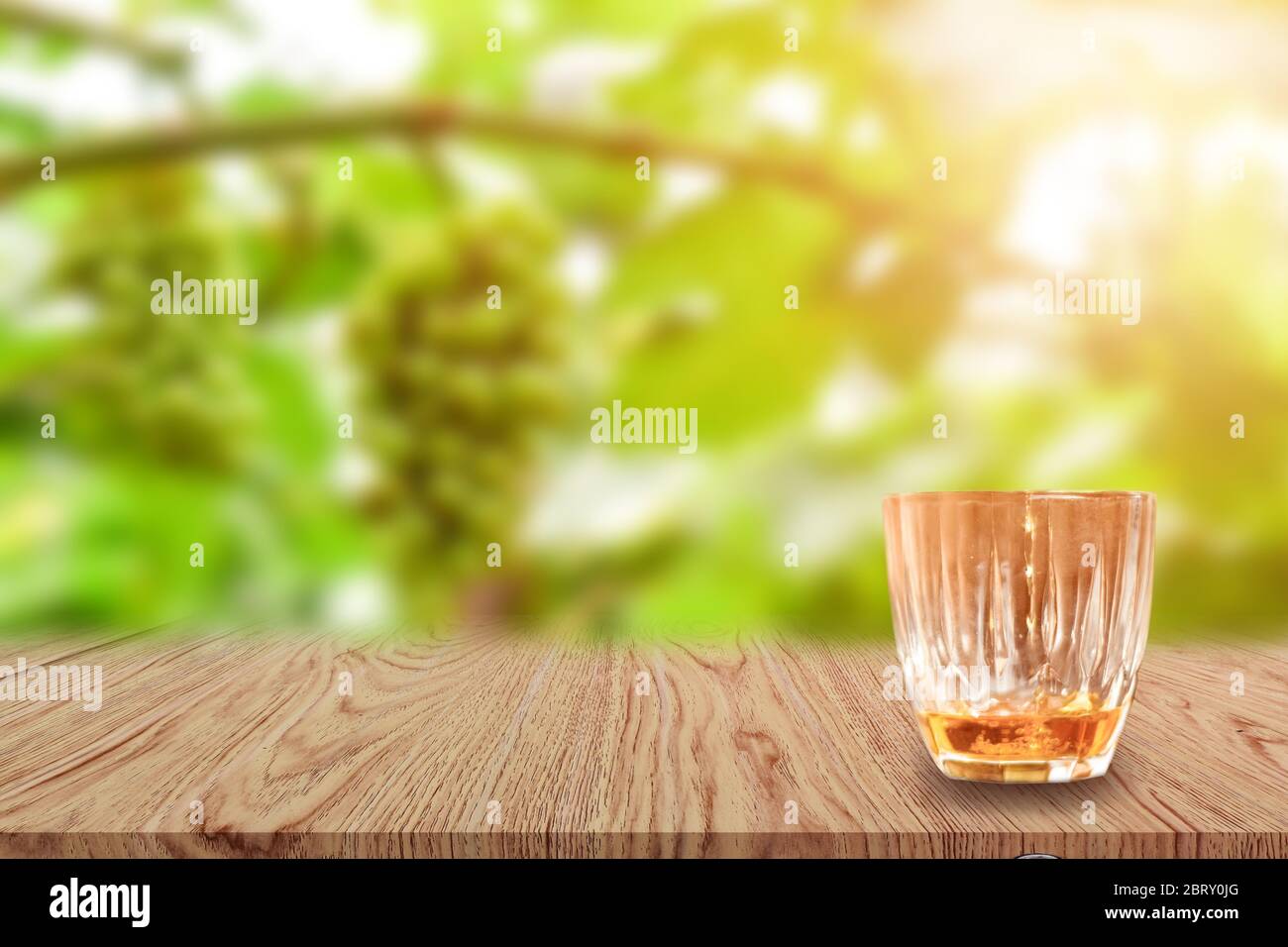Un bicchiere di Whiskey su un tavolo di legno e sfondo naturale sfocato chiaro. Foto Stock