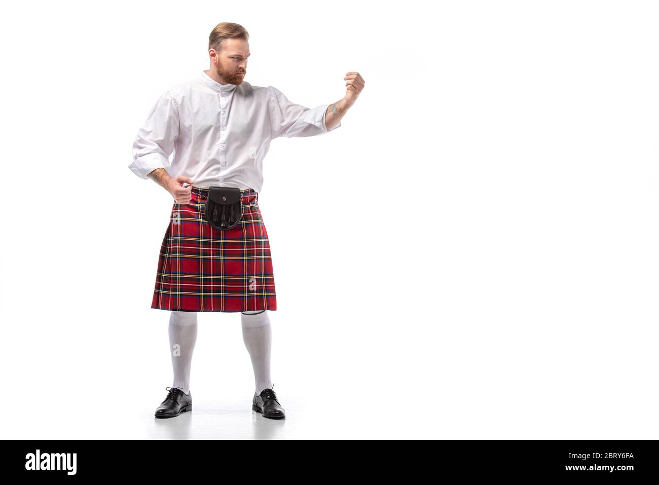 Uomo rosso scozzese serio in kilt rosso su sfondo bianco Foto Stock