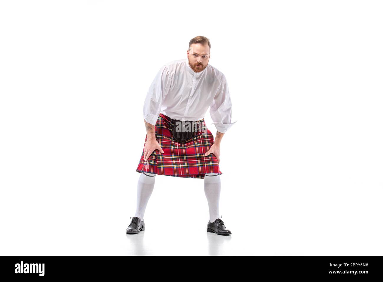 Uomo scozzese rosso in kilt rosso in posa su sfondo bianco Foto Stock