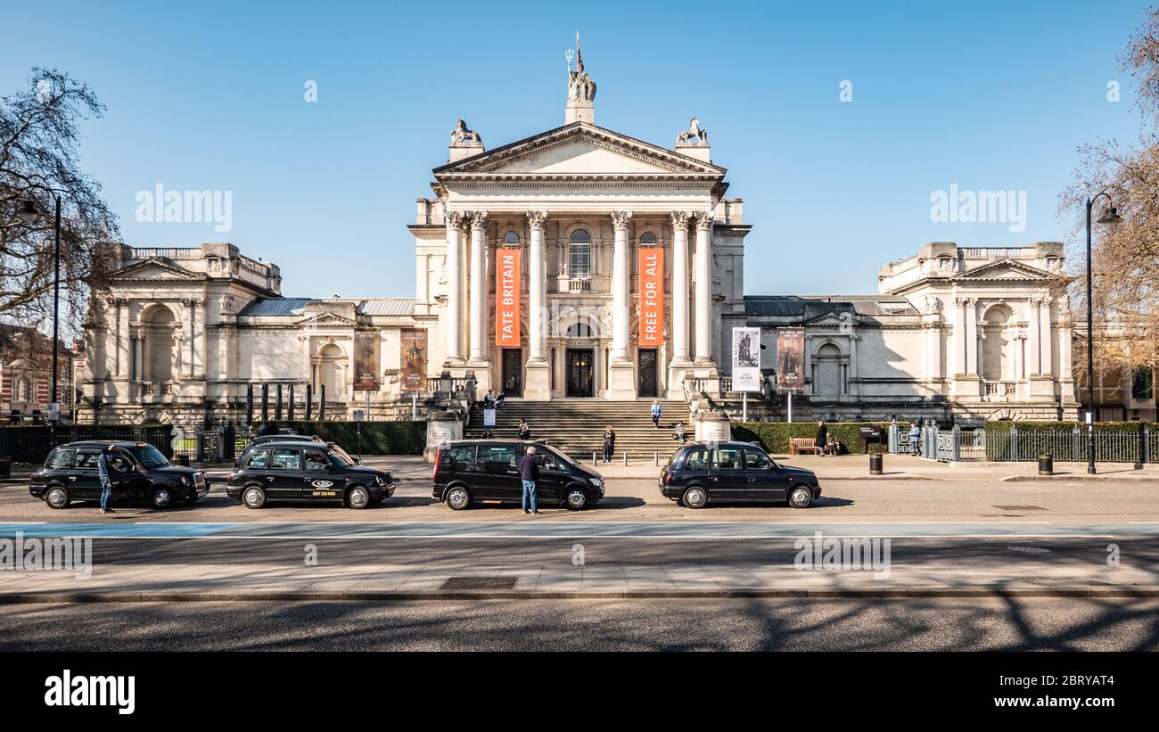 Il museo e la galleria Tate Britain a Millbank, Westminster, con i tradizionali taxi neri parcheggiati in attesa di un biglietto. Londra, Inghilterra. Foto Stock