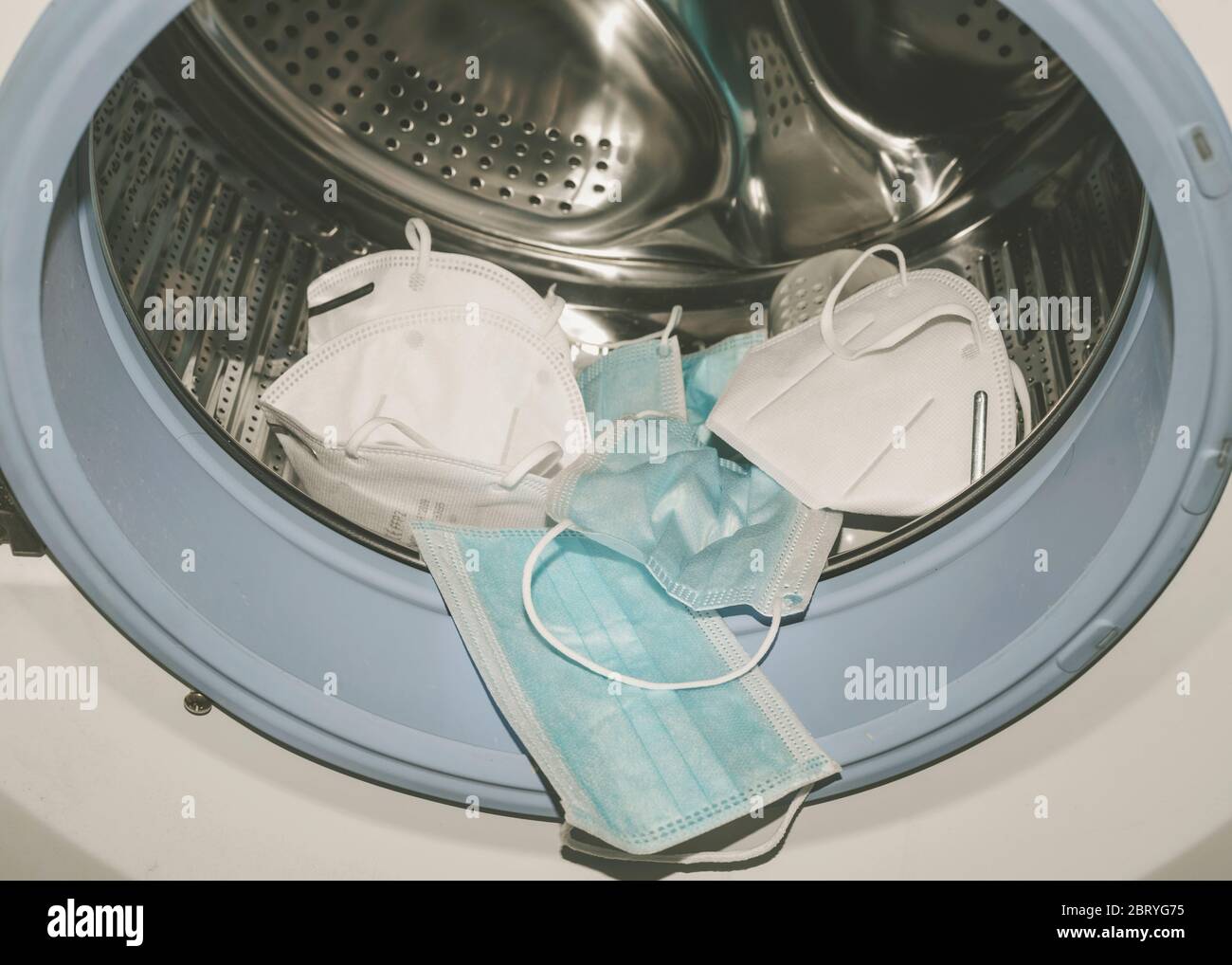 maschere mediche su una lavatrice per la pulizia a casa Foto Stock