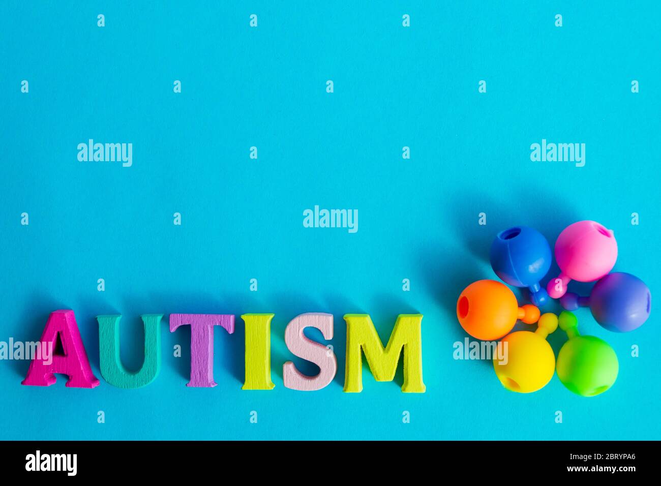 La parola autismo da lettere multicolore. I perline di puzzle sono piegati a forma di fiore su sfondo blu. Giorno autismo. Disordismo dello spettro autistico Foto Stock