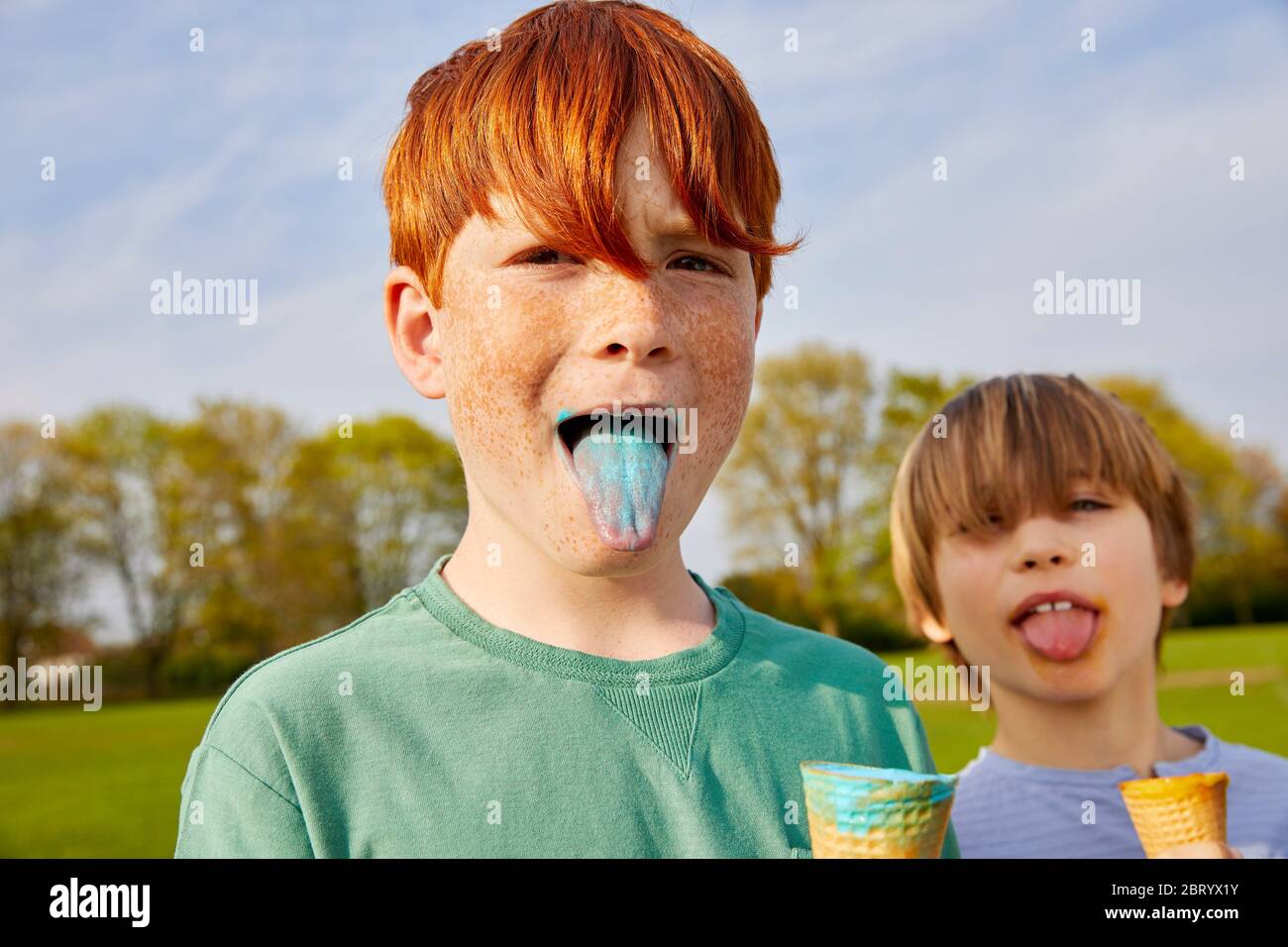 Due ragazzi in piedi all'aperto, mangiando coni gelato. Foto Stock