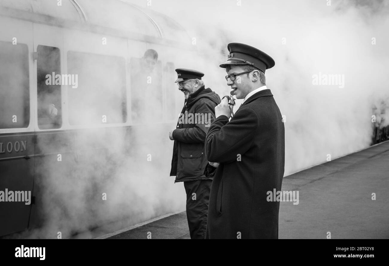 Vista sulla piattaforma monocromo e suggestiva del treno a vapore vintage britannico che parte dalla stazione di Kidderminster, la ferrovia storica della Severn Valley. Ferrovia in bianco e nero. Foto Stock