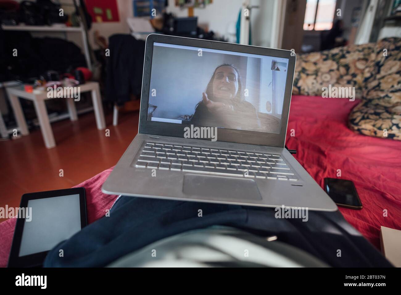 Uomo che ha chat online con un amico di sesso femminile utilizzando il computer portatile, mentre si auto-isola durante la crisi di Corona. Foto Stock