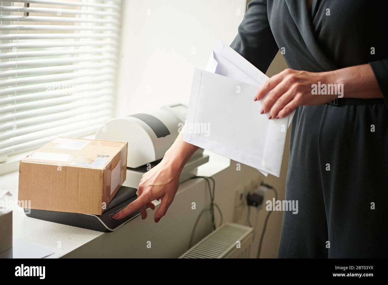 Una donna che pesa un pacco per la spedizione. Foto Stock