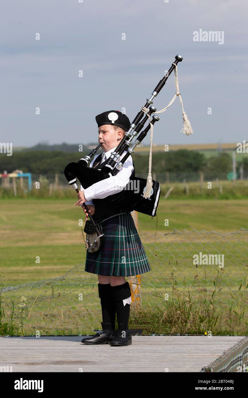 Giovane bagpier scozzese in abito tradizionale highland che gioca le pipe ai Halkirk Highland Games a Caithness, Scozia Foto Stock