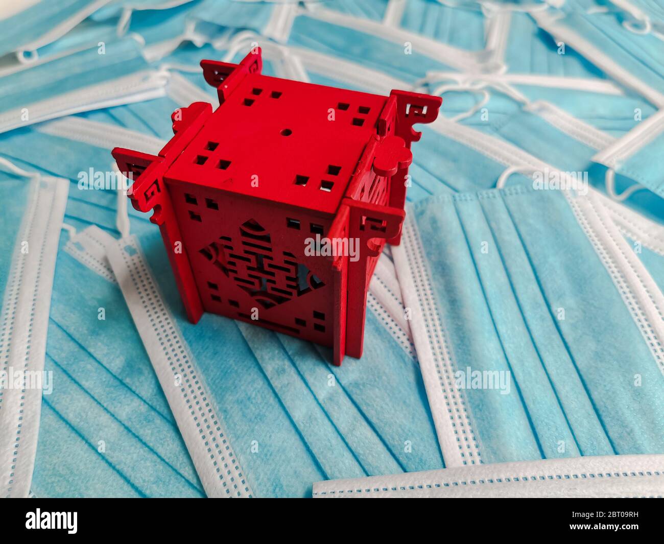 Padiglione in miniatura rosso che rappresenta la Cina su uno sfondo di maschere chirurgiche monouso blu Foto Stock