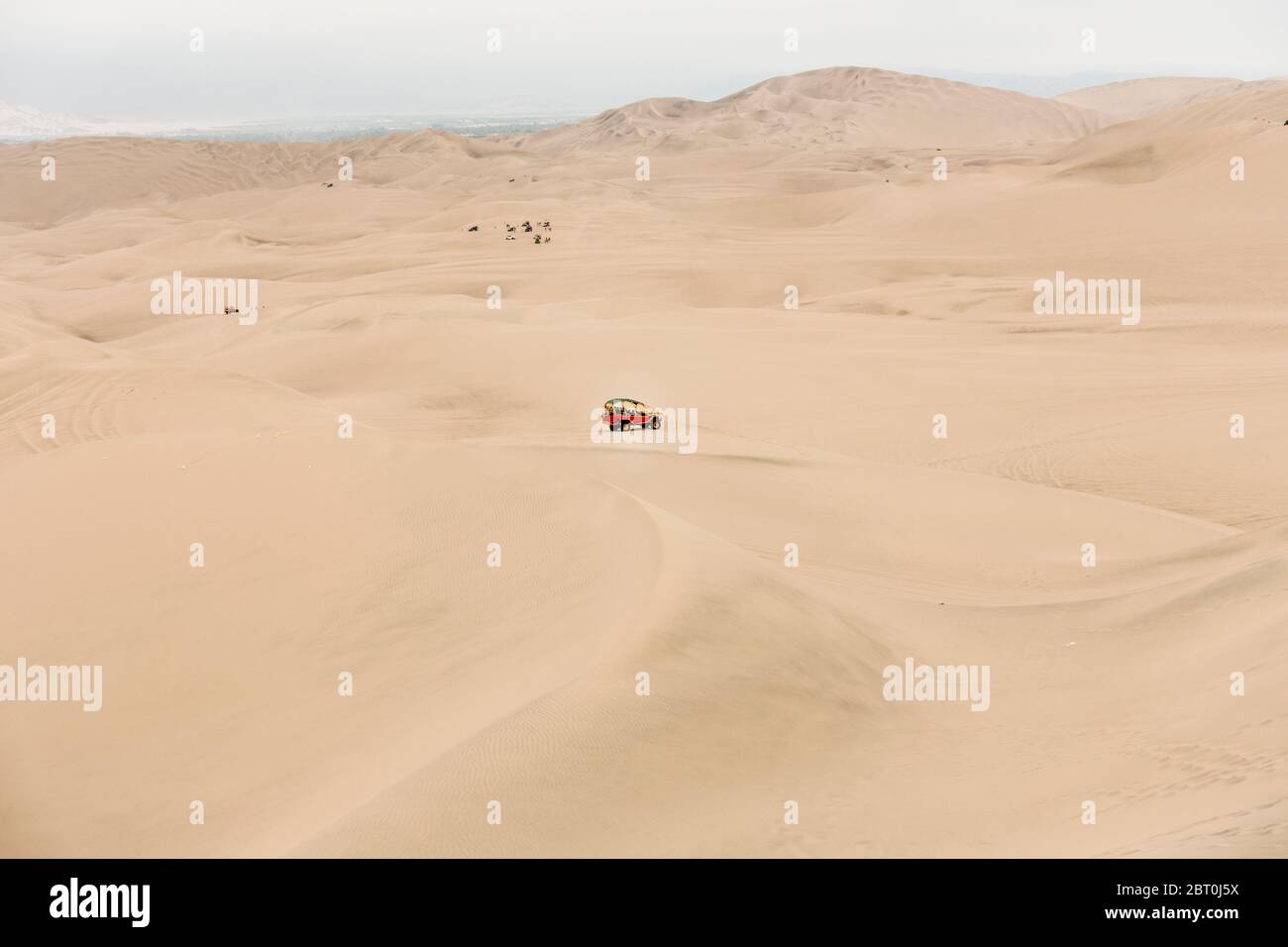 Paesaggio desertico con veicolo rosso a metà distanza vicino a Cusco, Perù. Foto Stock