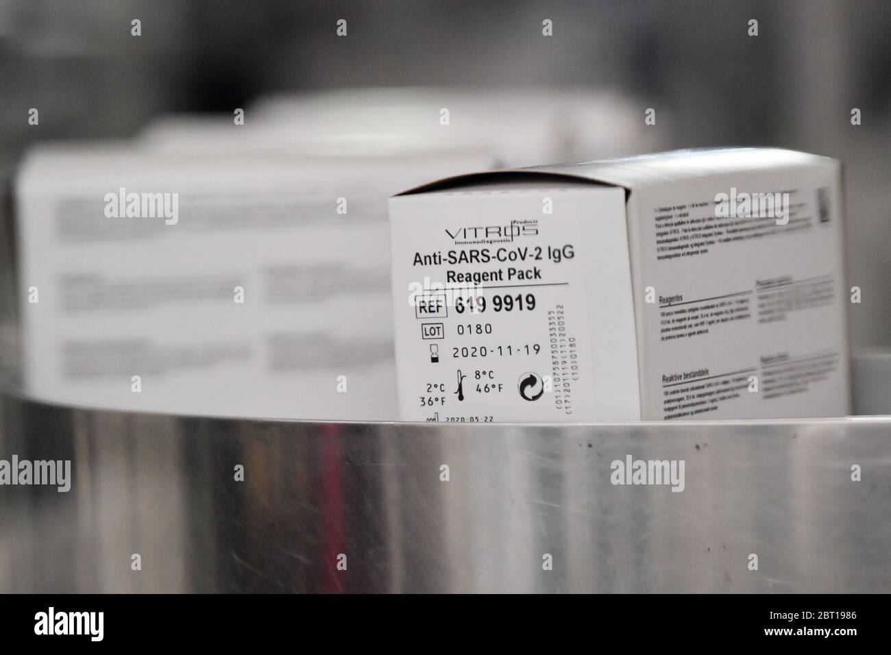 I kit per test anticorpali covid-19 in scatola si spostano lungo un trasportatore dietro gli schermi perspex sulla linea di produzione presso il laboratorio di test Ortho Clinical Diagnostics (OCD) di Pencoed in Galles. Foto Stock