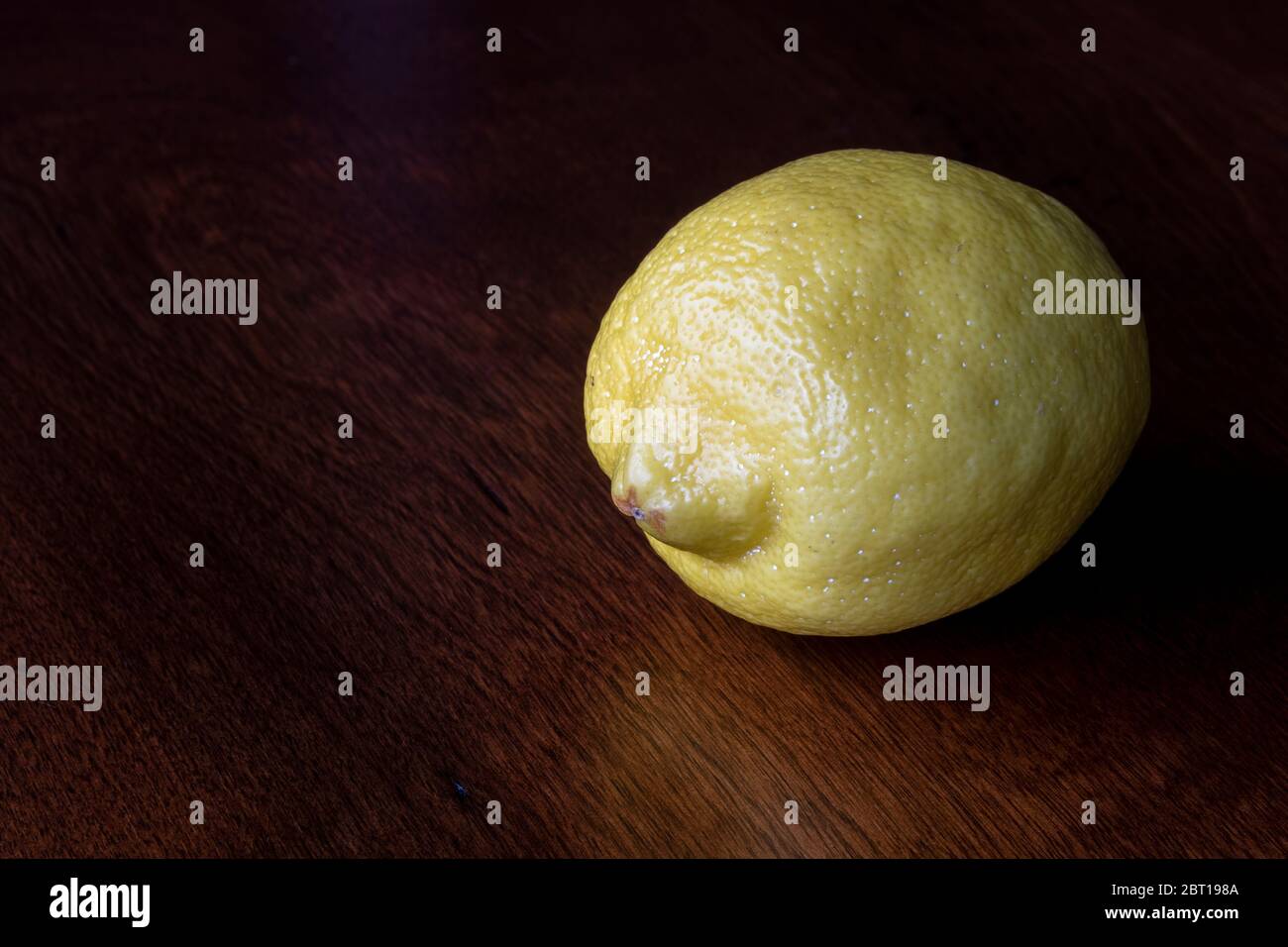 Un solo limone intero su un piano di legno Foto Stock