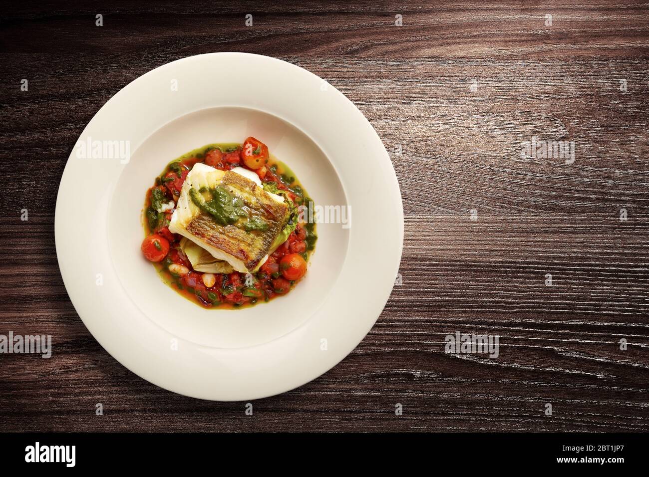 Direttamente sopra un'elegante piatto di pesce alla Nouvelle Cuisine su verdure su sfondo di legno Foto Stock