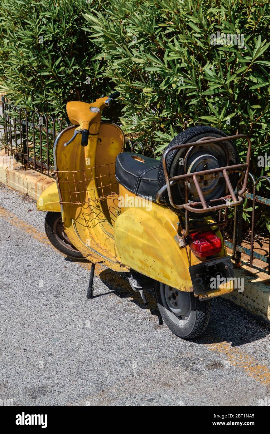 Vecchio scooter giallo d'epoca sulla via greca. Foto Stock