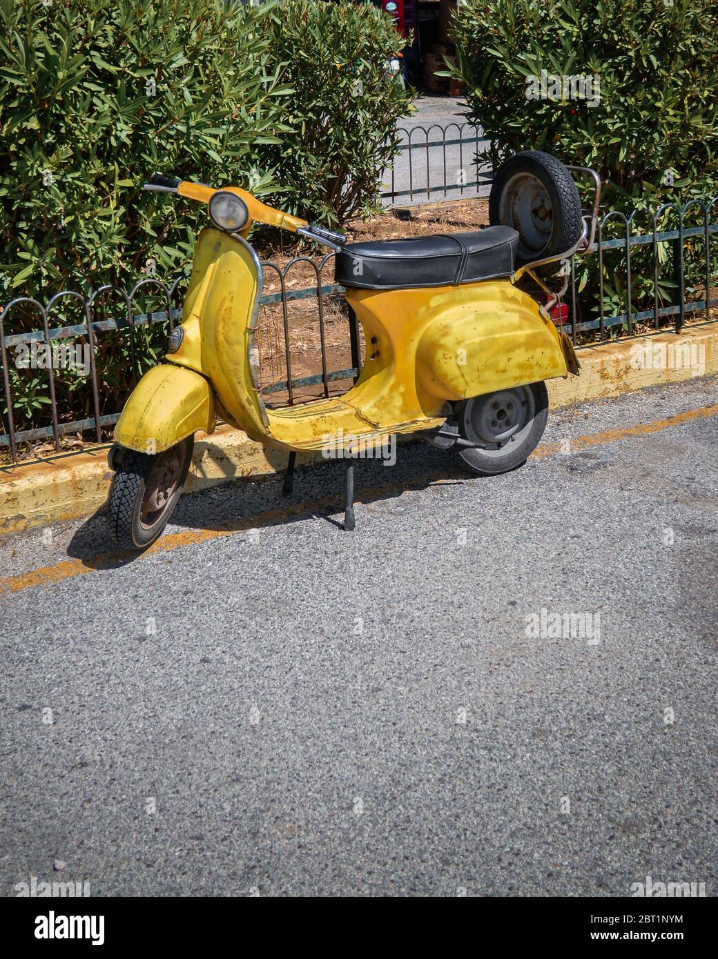 Vecchio scooter giallo d'epoca sulla via greca. Foto Stock