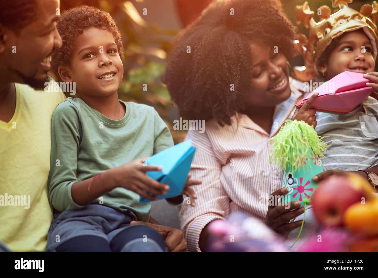 Afro-american giovane famiglia celebrare compleanno party.girl e ragazzo giocare con barche di carta. Foto Stock