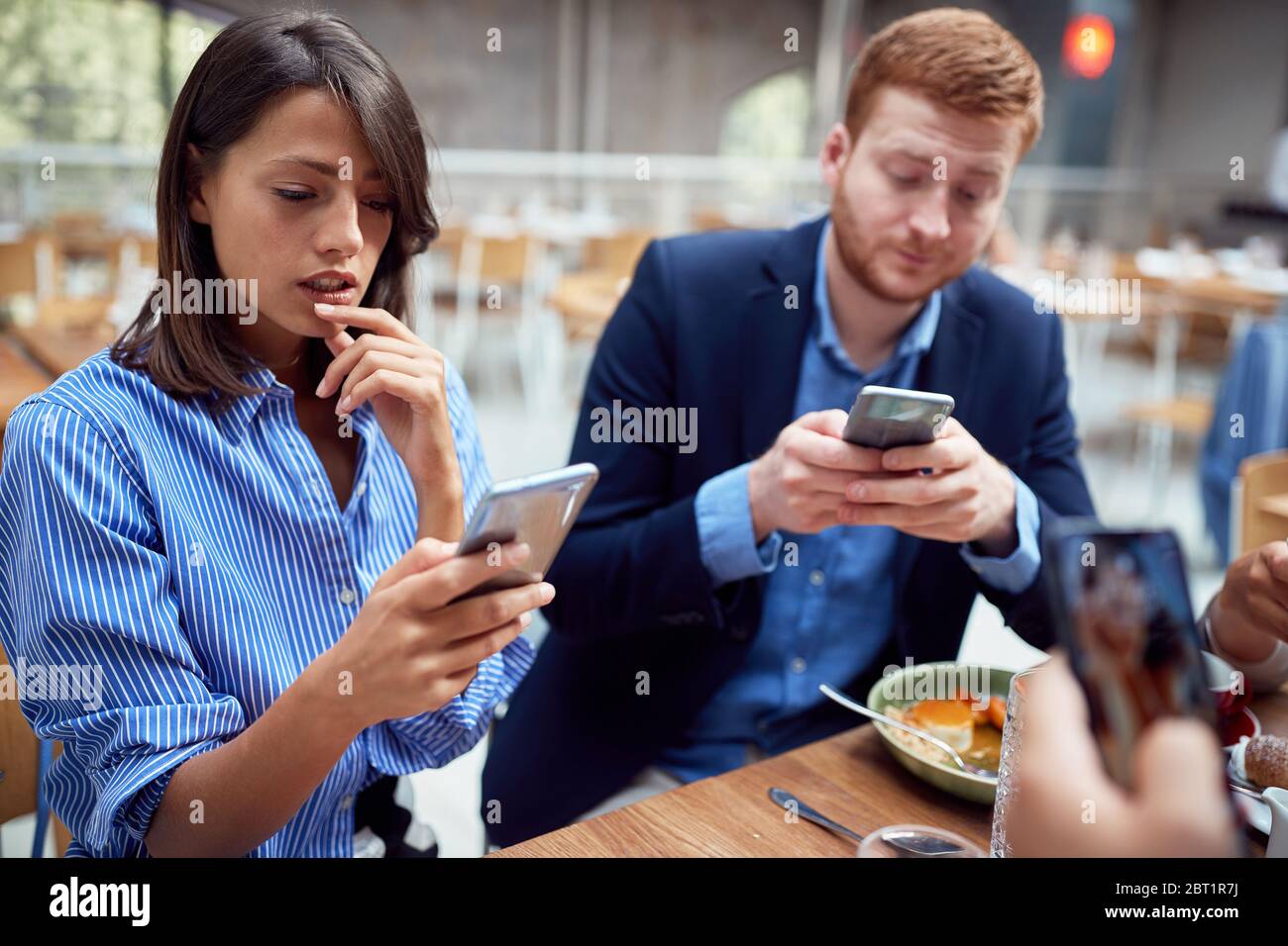 persone a pranzo nei loro mondi, distratti l'uno dall'altro dai telefoni cellulari. non presente, problemi sociali, vittime della tecnologia moderna Foto Stock