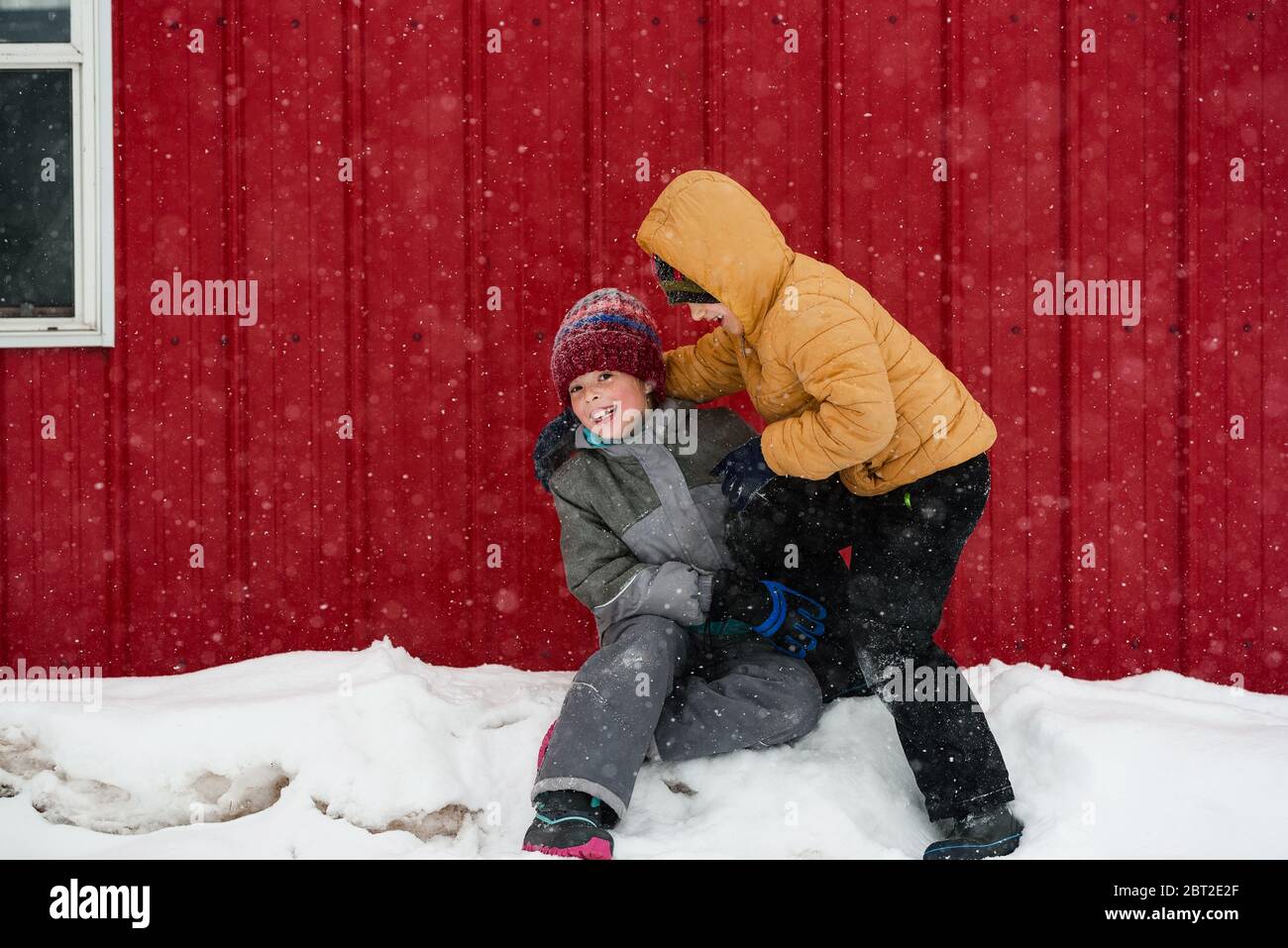 Due bambini che giocano nella neve fuori da una casa, USA Foto Stock