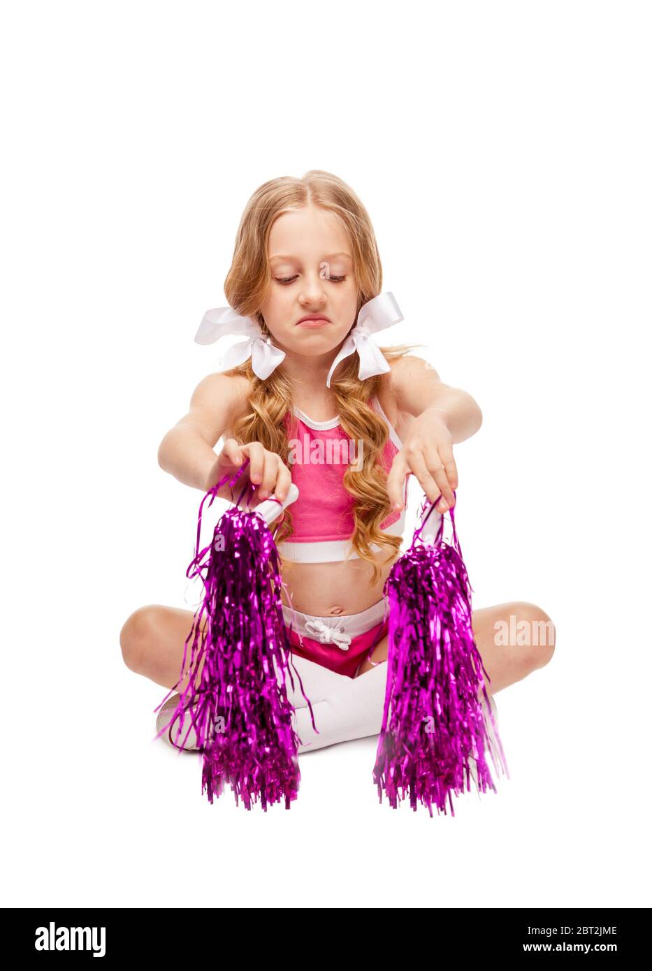 una ragazza sotto forma di cheerleader guarda i pom pom come se fosse sgradevole Foto Stock