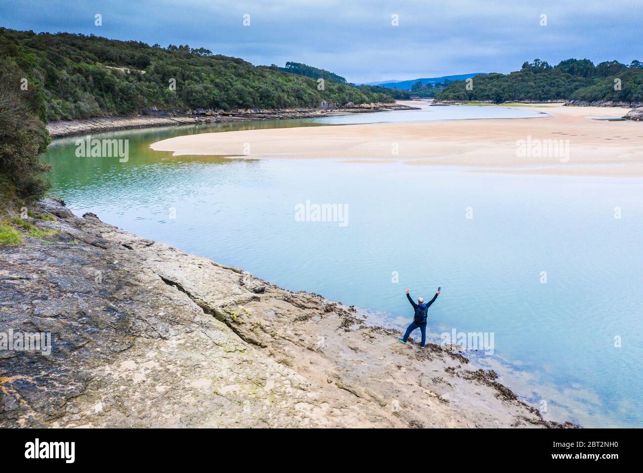 Uomo, fiume e sedimenti sabbiosi in bassa marea vicino al mare. Foto Stock