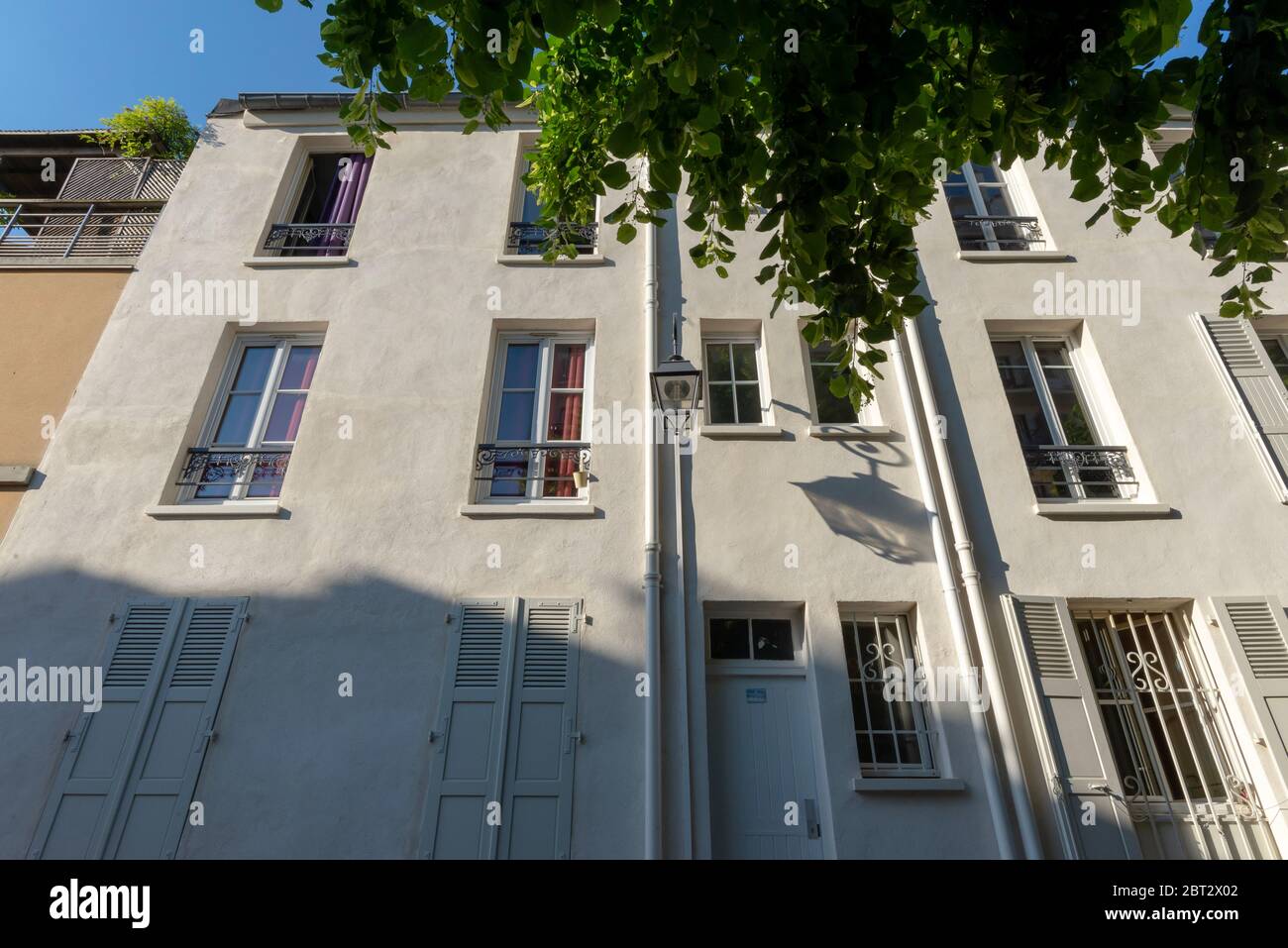 Vista ad angolo basso di una facciata beige pallido con lanterna esterna che colma la propria ombra, Butte-aux-Cailles, Parigi, Francia Foto Stock