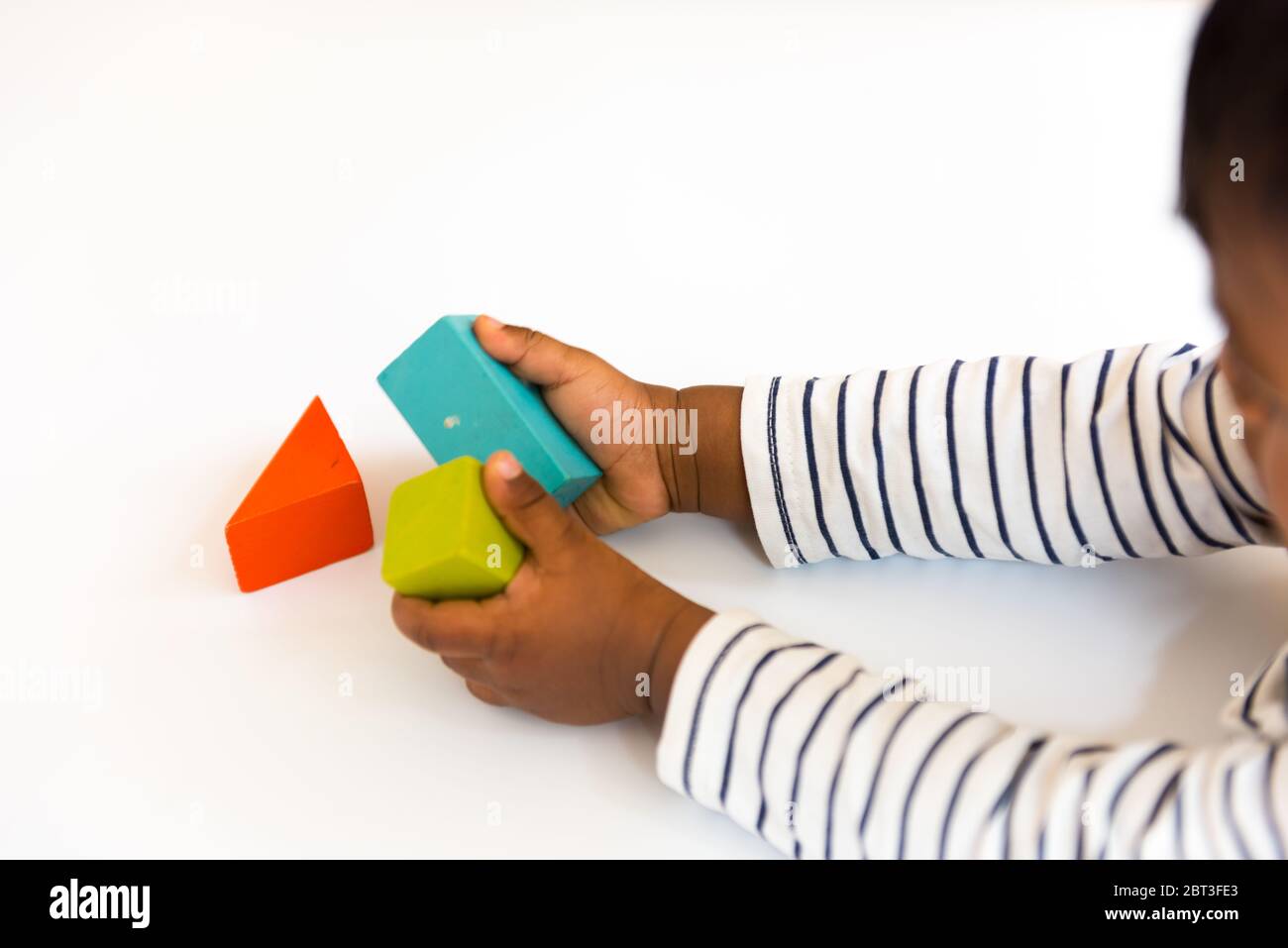 Bambino di un anno che gioca con colorati blocchi di legno da costruzione sul tavolo Foto Stock