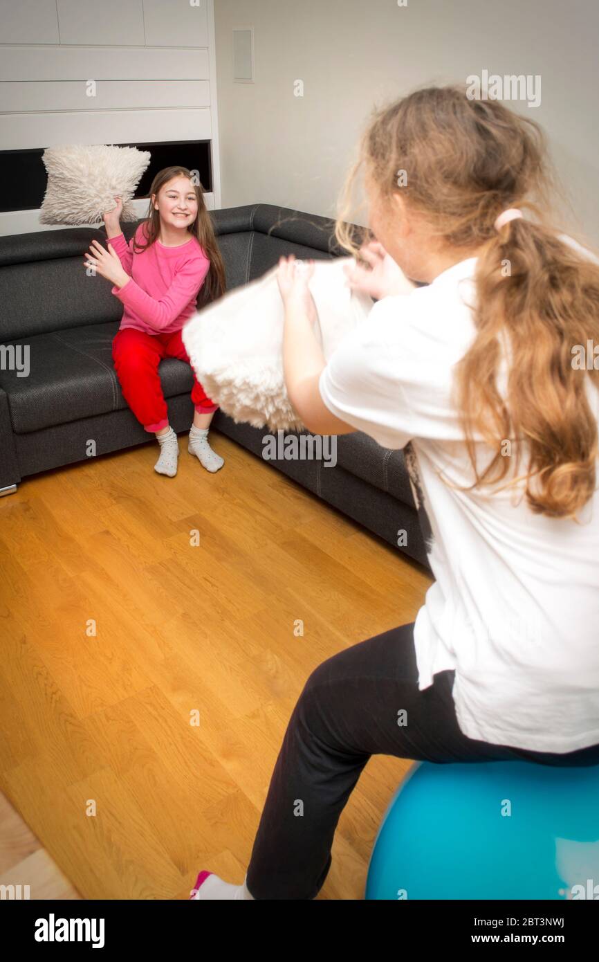 Le sorelle felici che giocano a cuscino combattono divertendosi a casa. Foto Stock