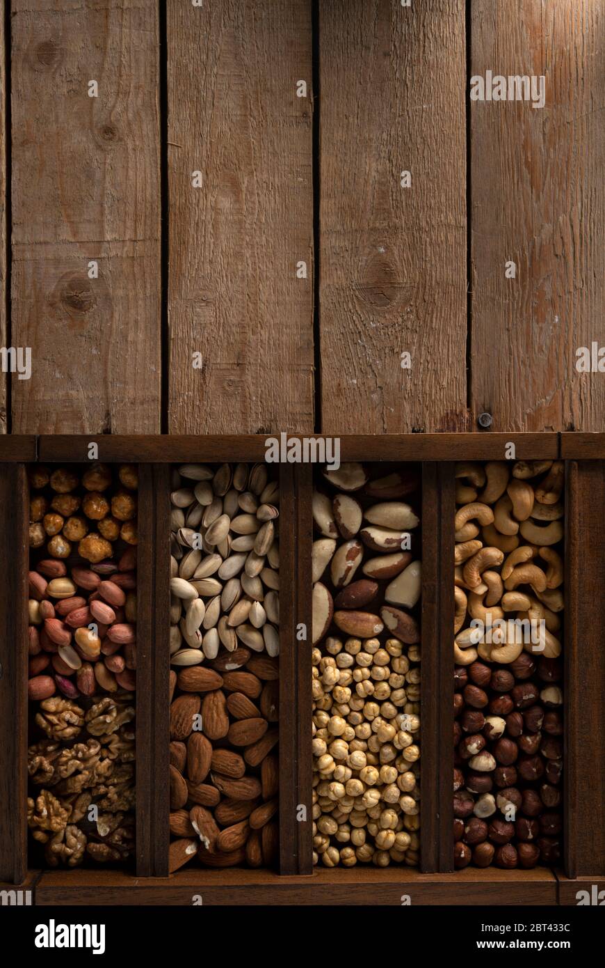 Nocciole, pistacchio, noci, ceci arrostiti, arachidi e molto altro in una scatola di legno su un tavolo di legno con posto per il logo Foto Stock